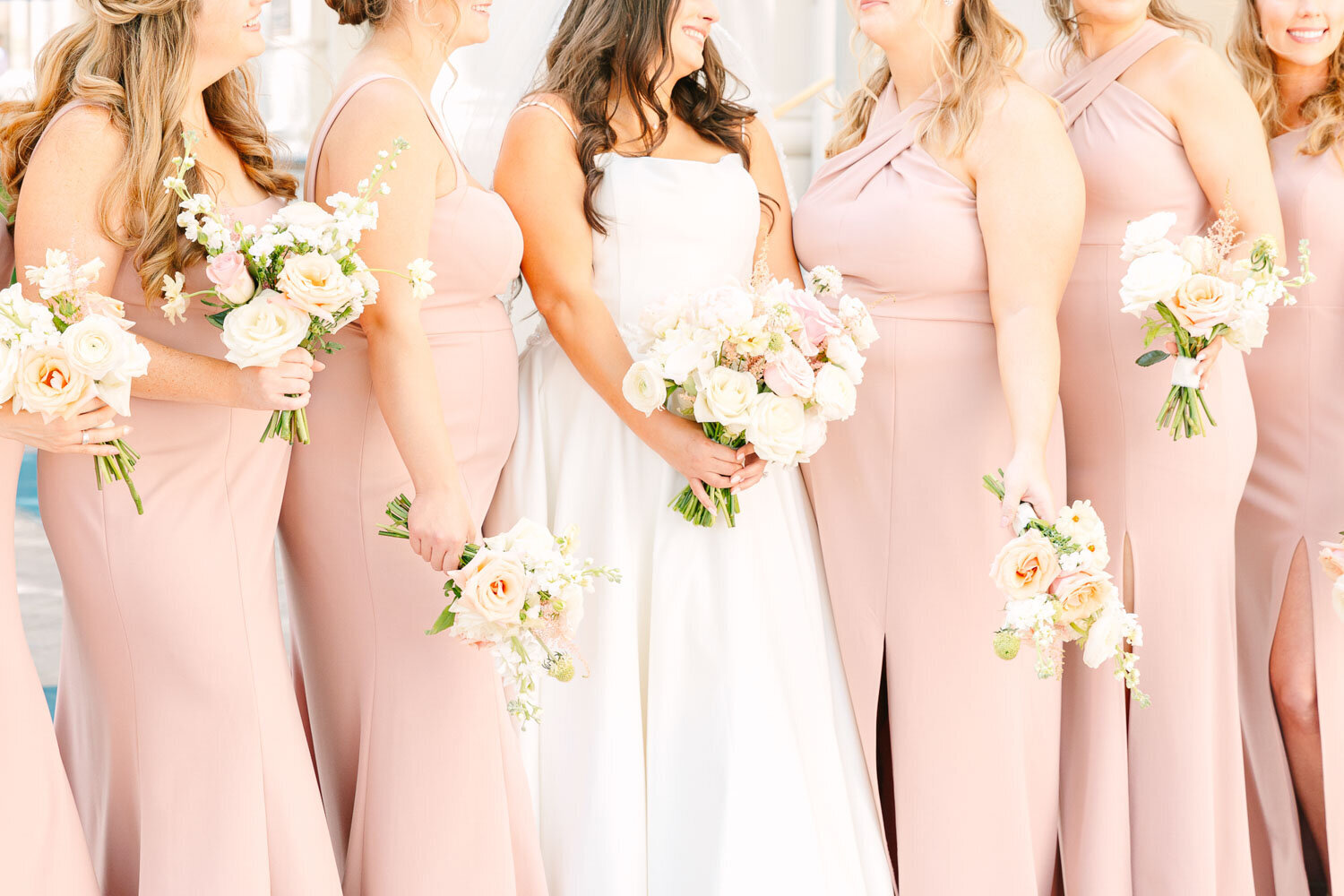Bride surrounded by bridesmaids in blush pink dresses