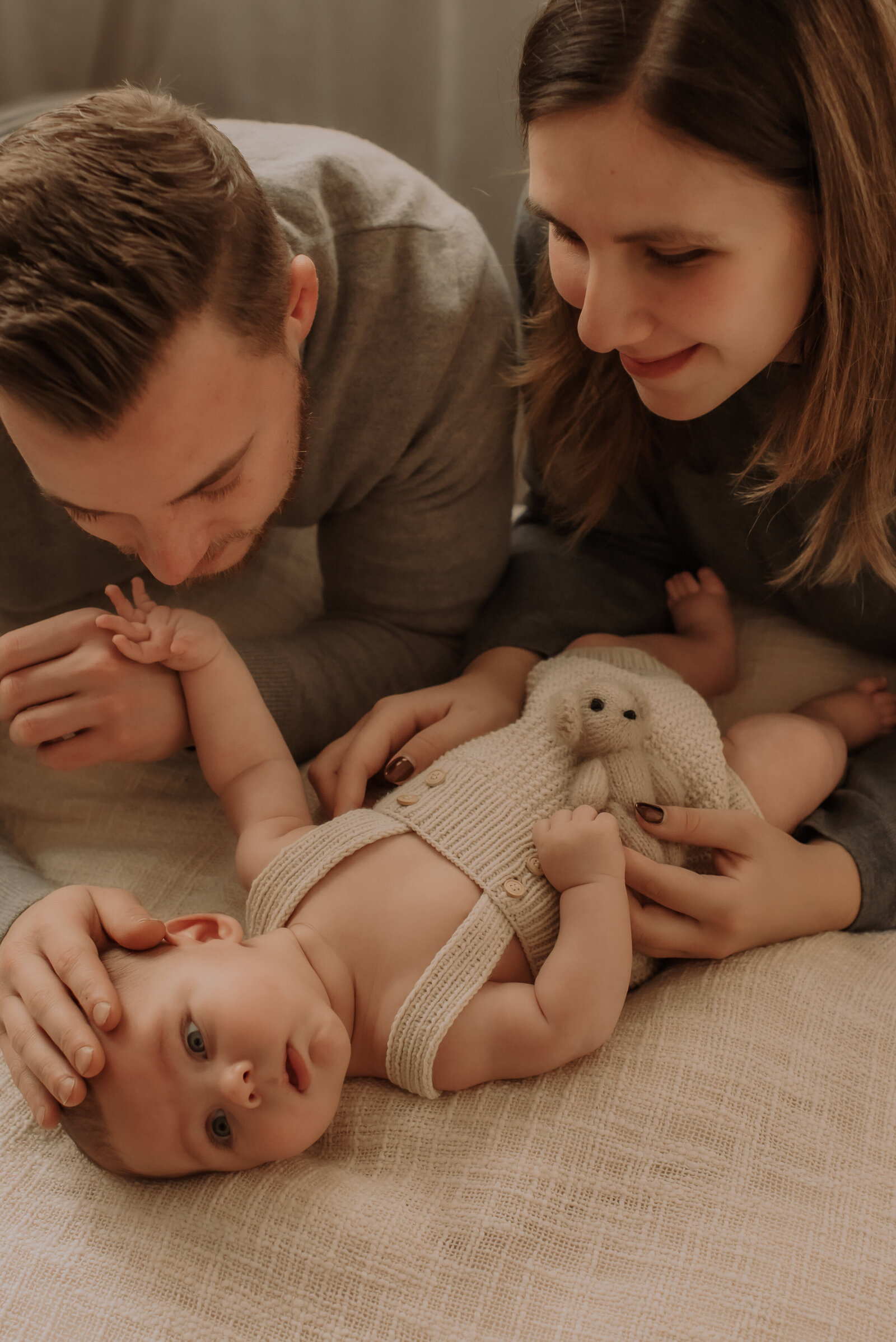 Mama en papa kijken liefdevol naar hun zoontje tijdens familiefotoshoot