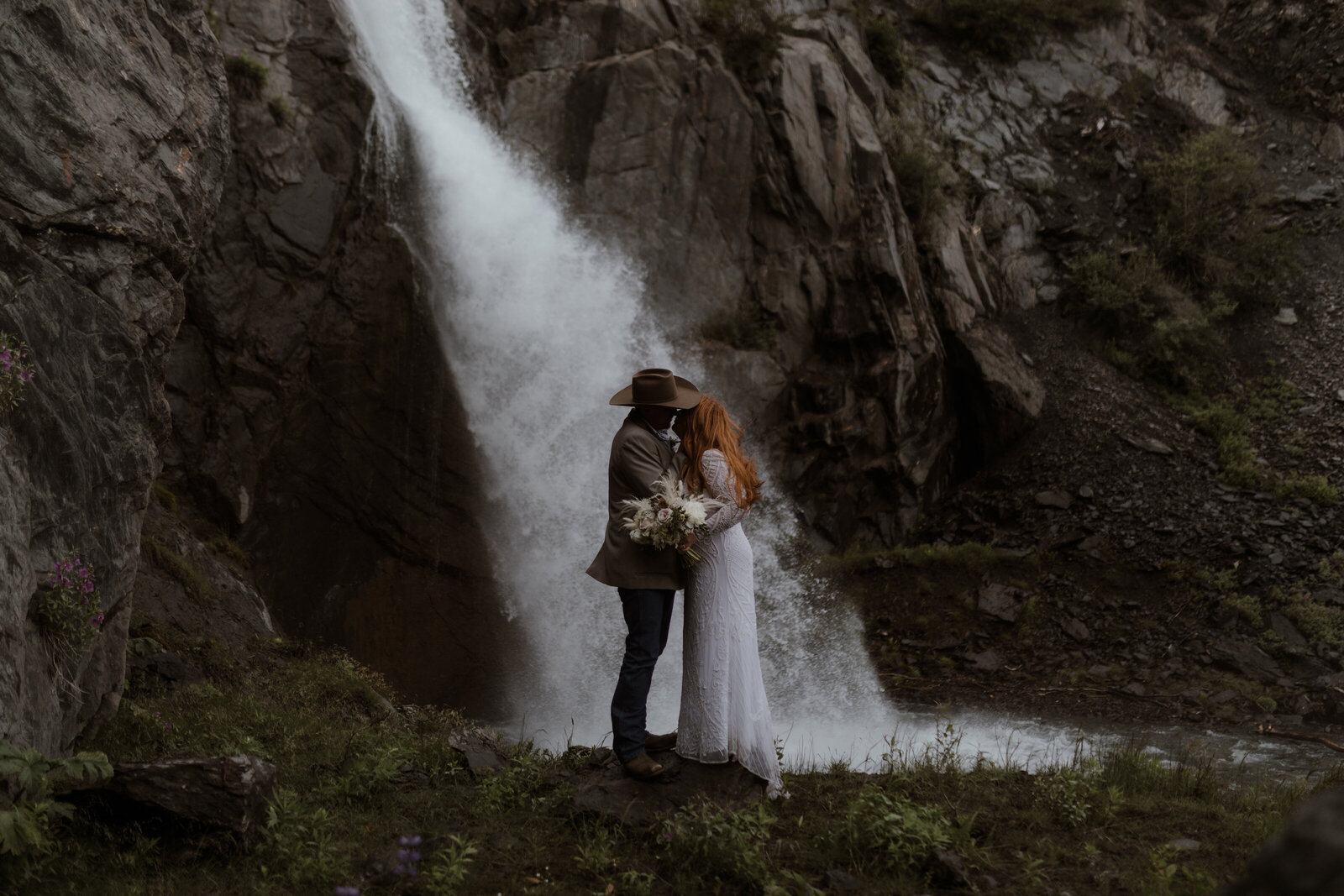 Bride and groom kissing by waterfall