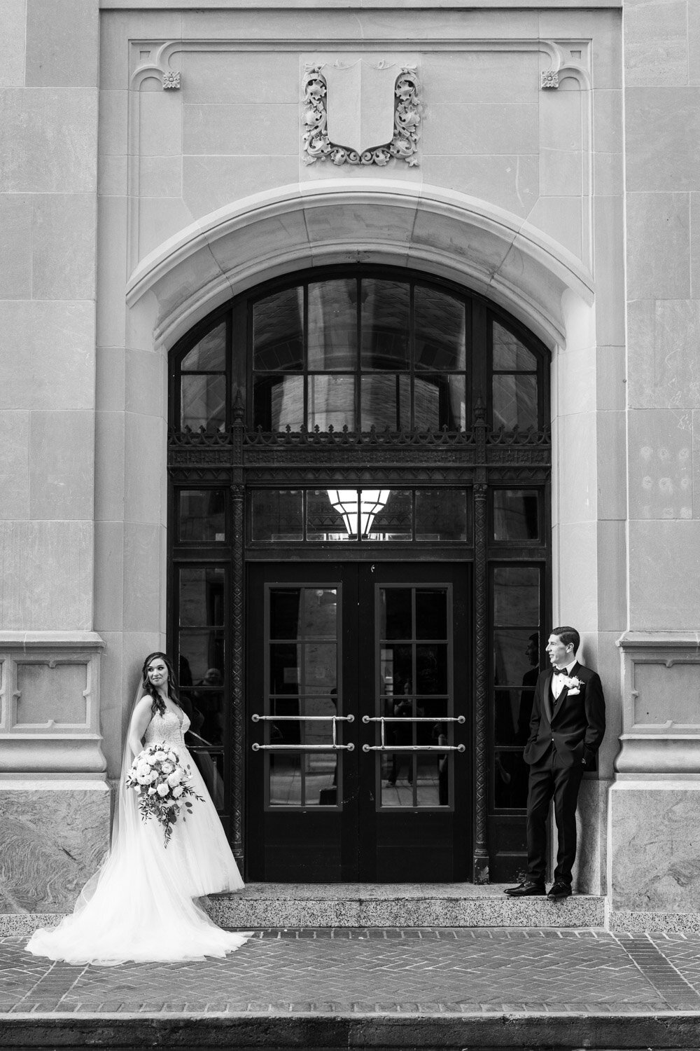 Bride and groom standing by large window in downtown New Orleans
