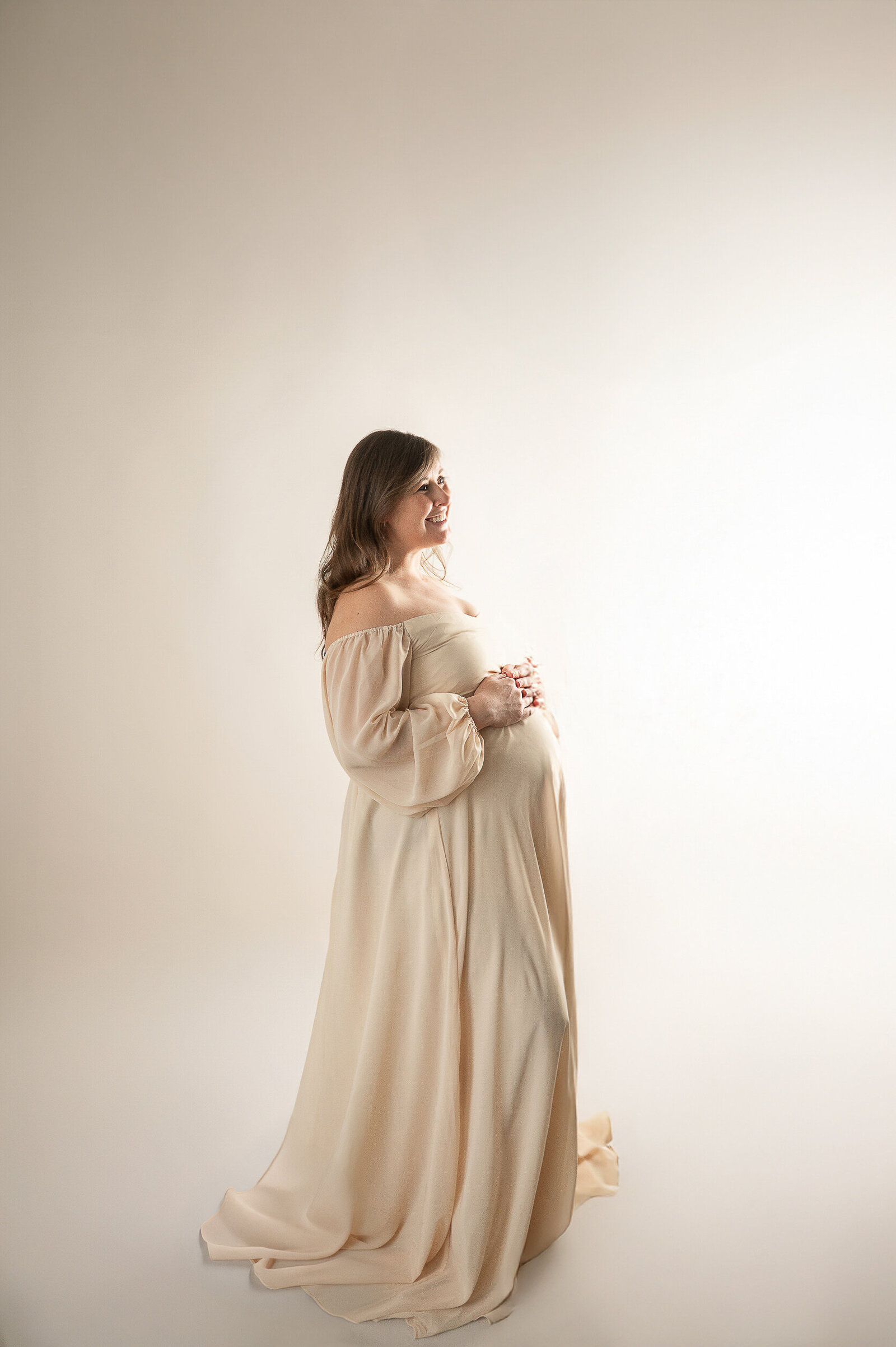 Elegant studio maternity portrait of a glowing mom-to-be in a neutral-toned dress, captured in Baltimore's top newborn and maternity photography studio.