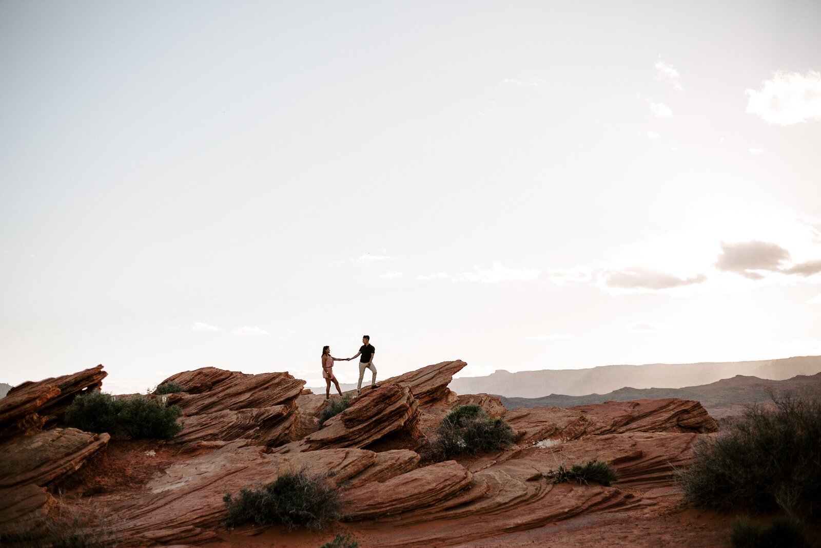 Couple holding hands standing on a red rock during their Arizona Engagement Session