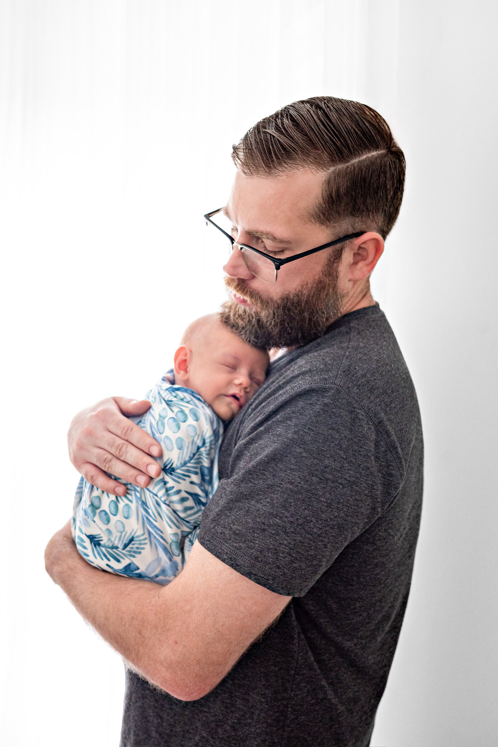 A father holding his newborn baby during newborn photos in a studio in Huntsville