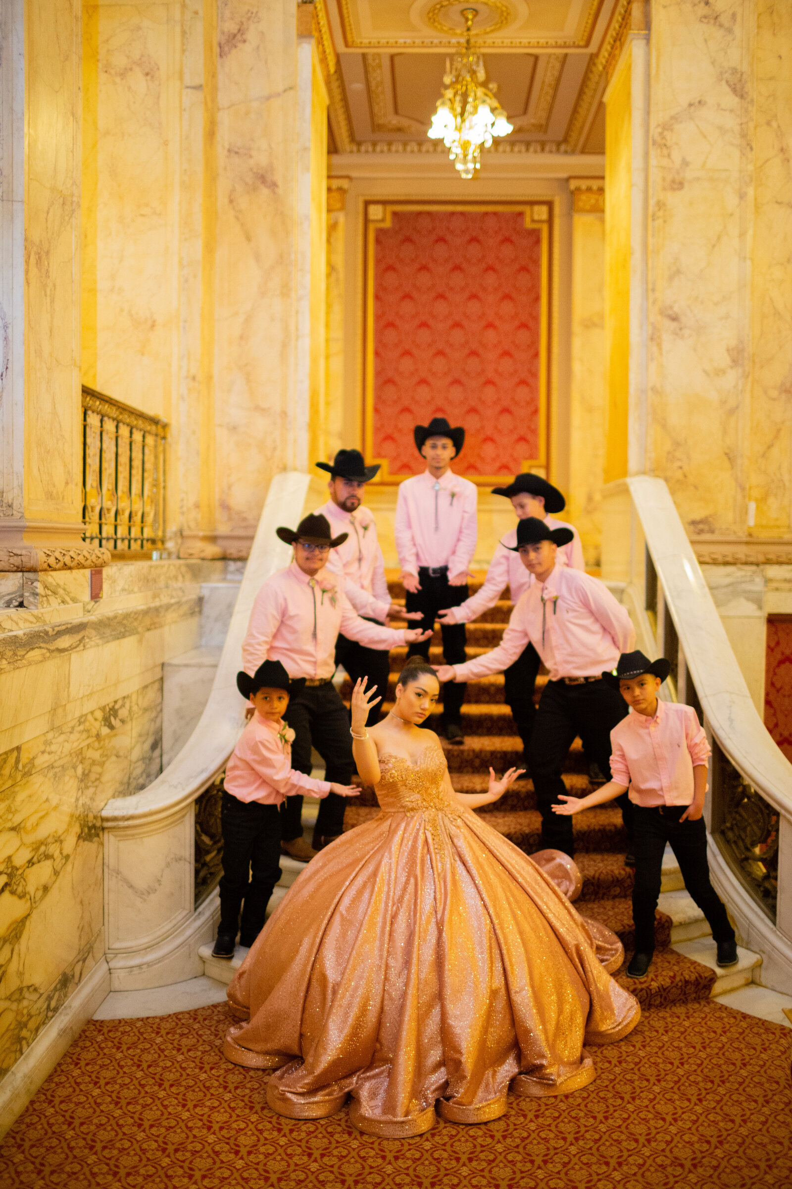 A stunning group portrait of a quinceañera with her chambelanes on the grand staircase of the Ohio Theater at Playhouse Square in Cleveland, Ohio. Capturing the elegance of the celebration and the grandeur of this historic venue.