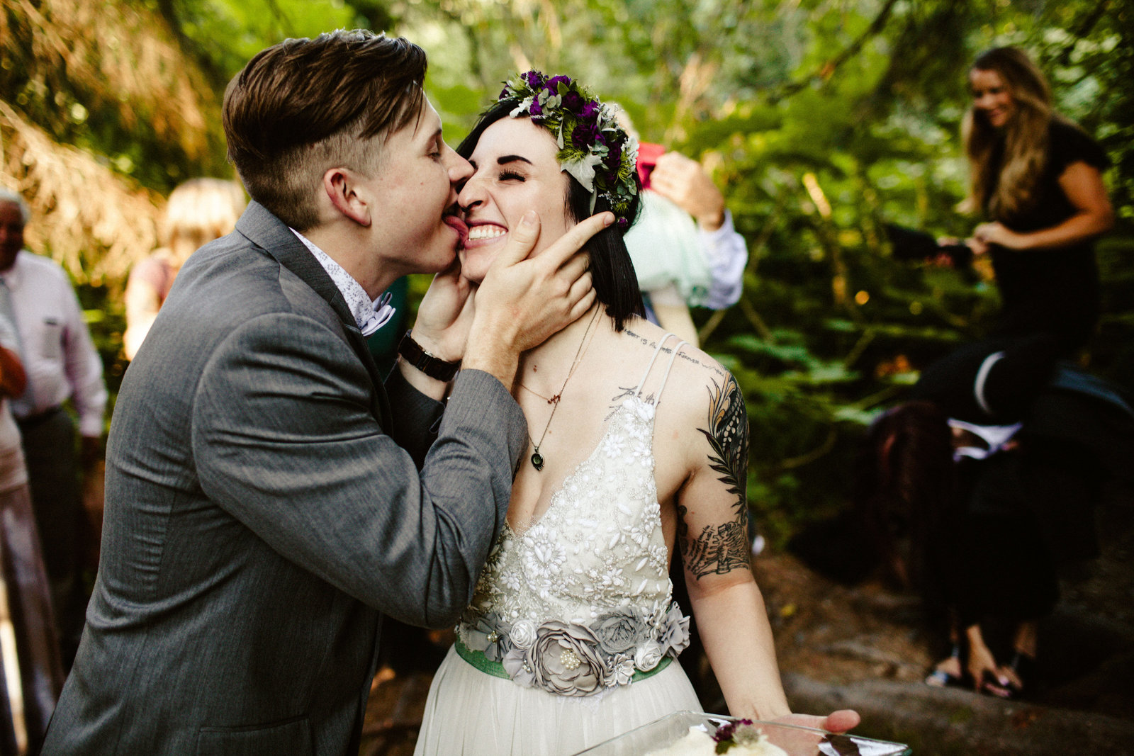 groom licks wedding cake off of brides face in girdwood forest