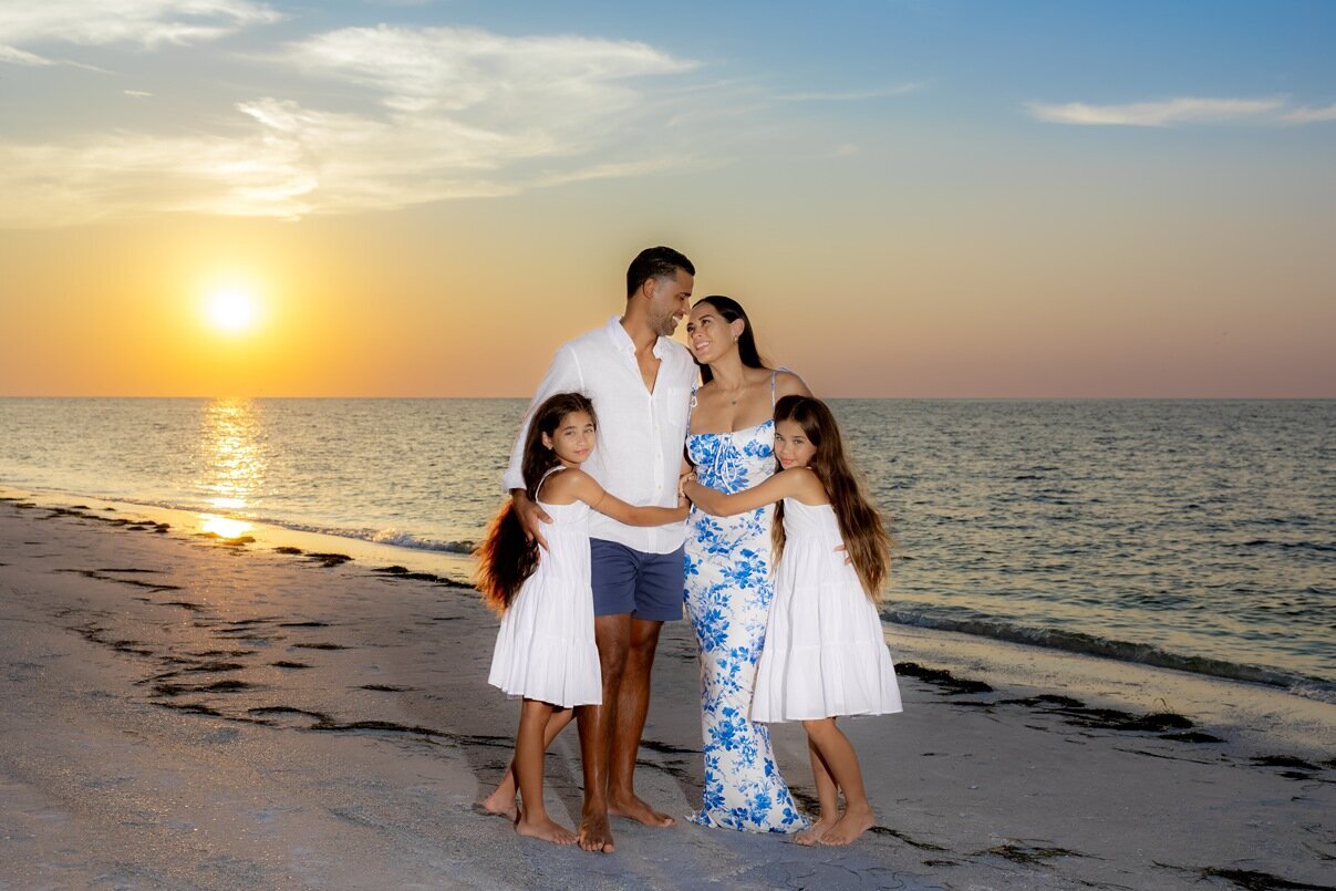 Family of four dressed in blues and whites on the beach at sunset by Sarasota photographer, Love and Style Photography
