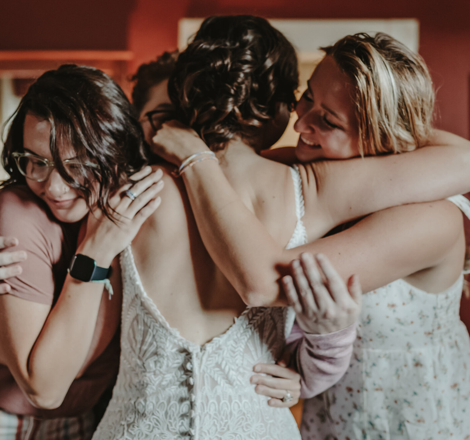 A bride hugs her friends after putting on her wedding dress