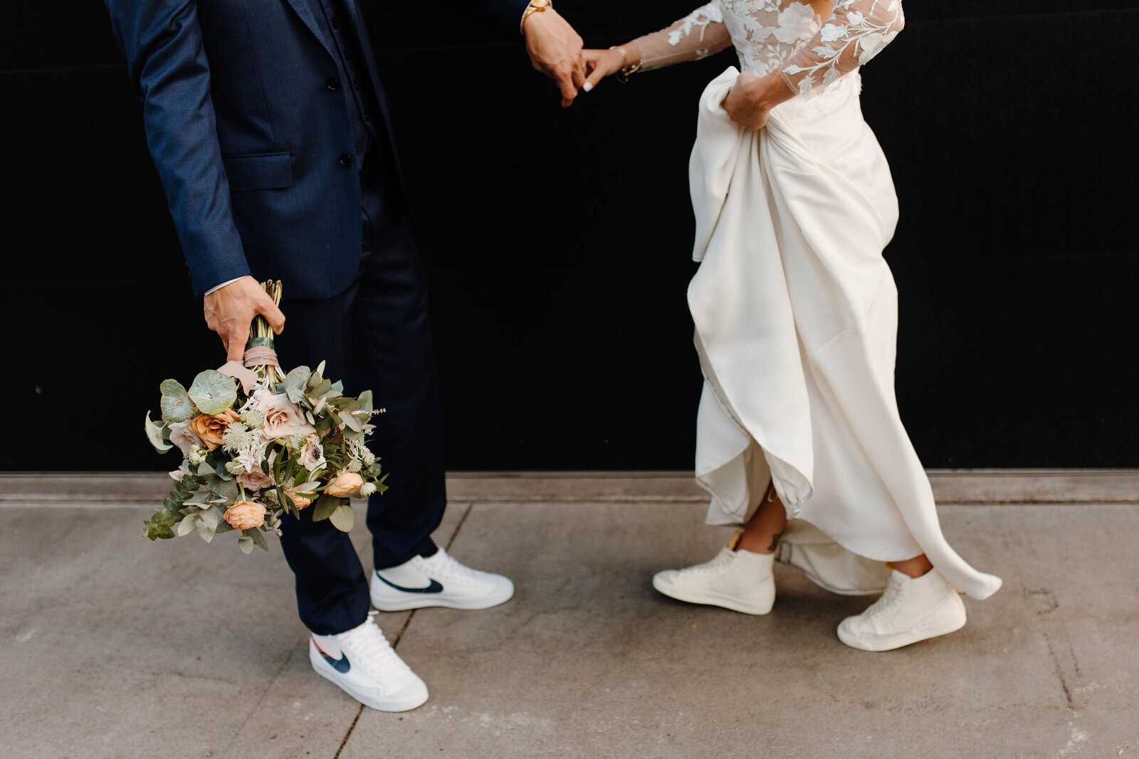 bride and groom with sneakers on holding hands