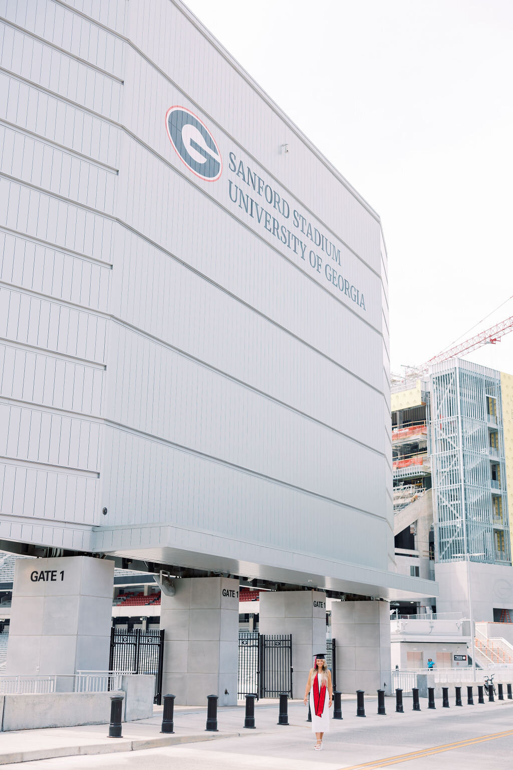 Girl in graduation cap stands outside Sanford Stadium
