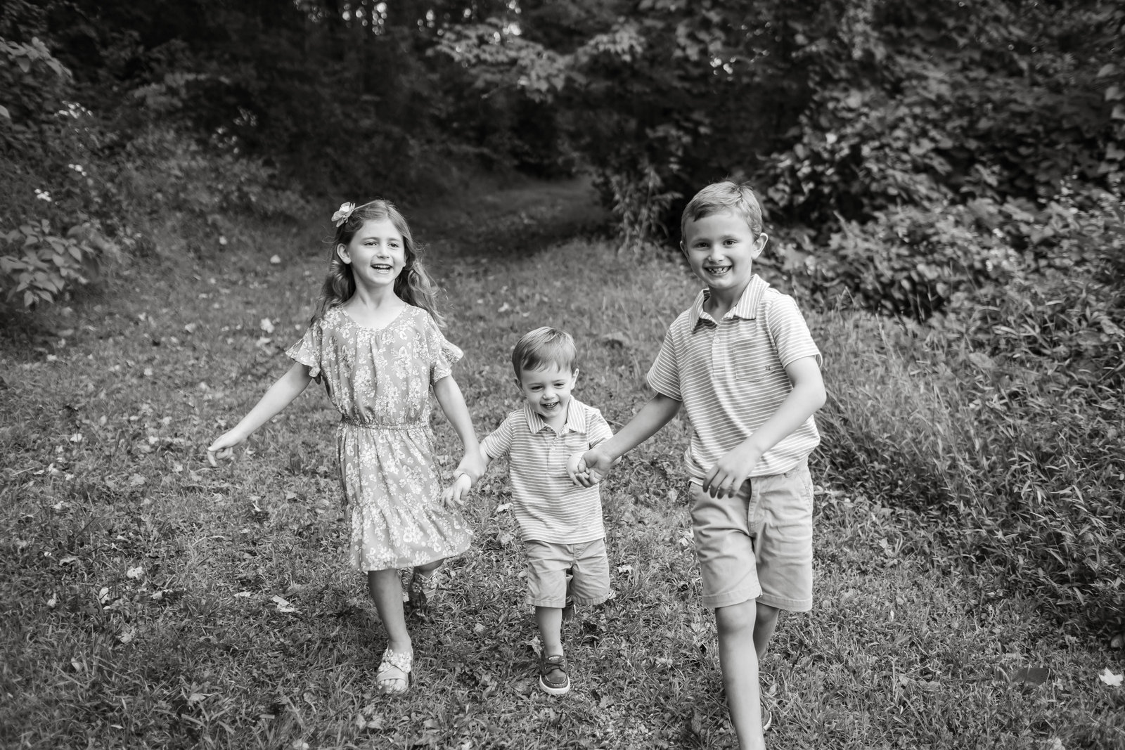 three siblings run through the woods in blueberry park in the north hills of pittsburgh
