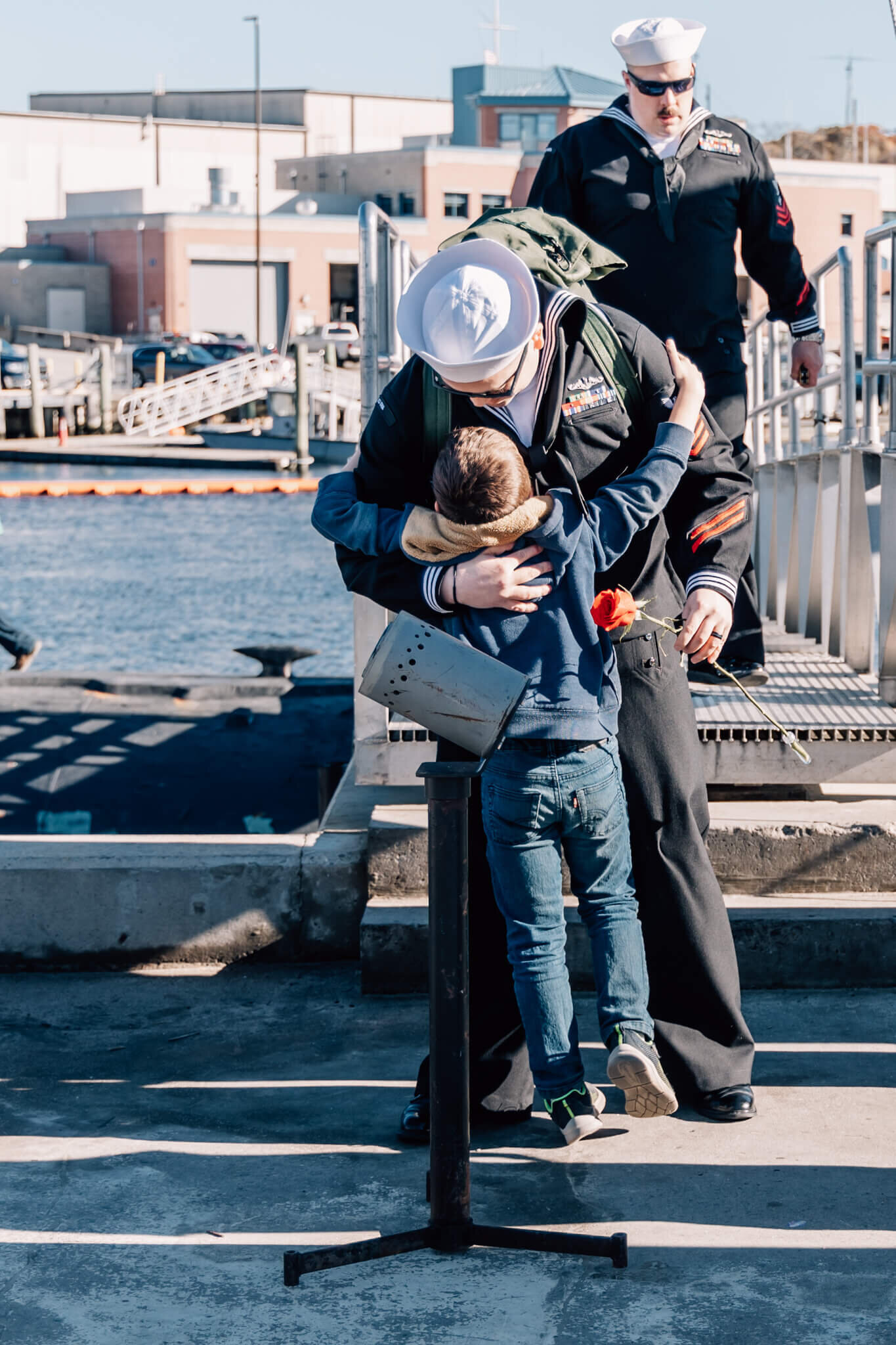 Naval petty officer hugs child while stepping off brow of USS North Dakota after 7 month deployment.