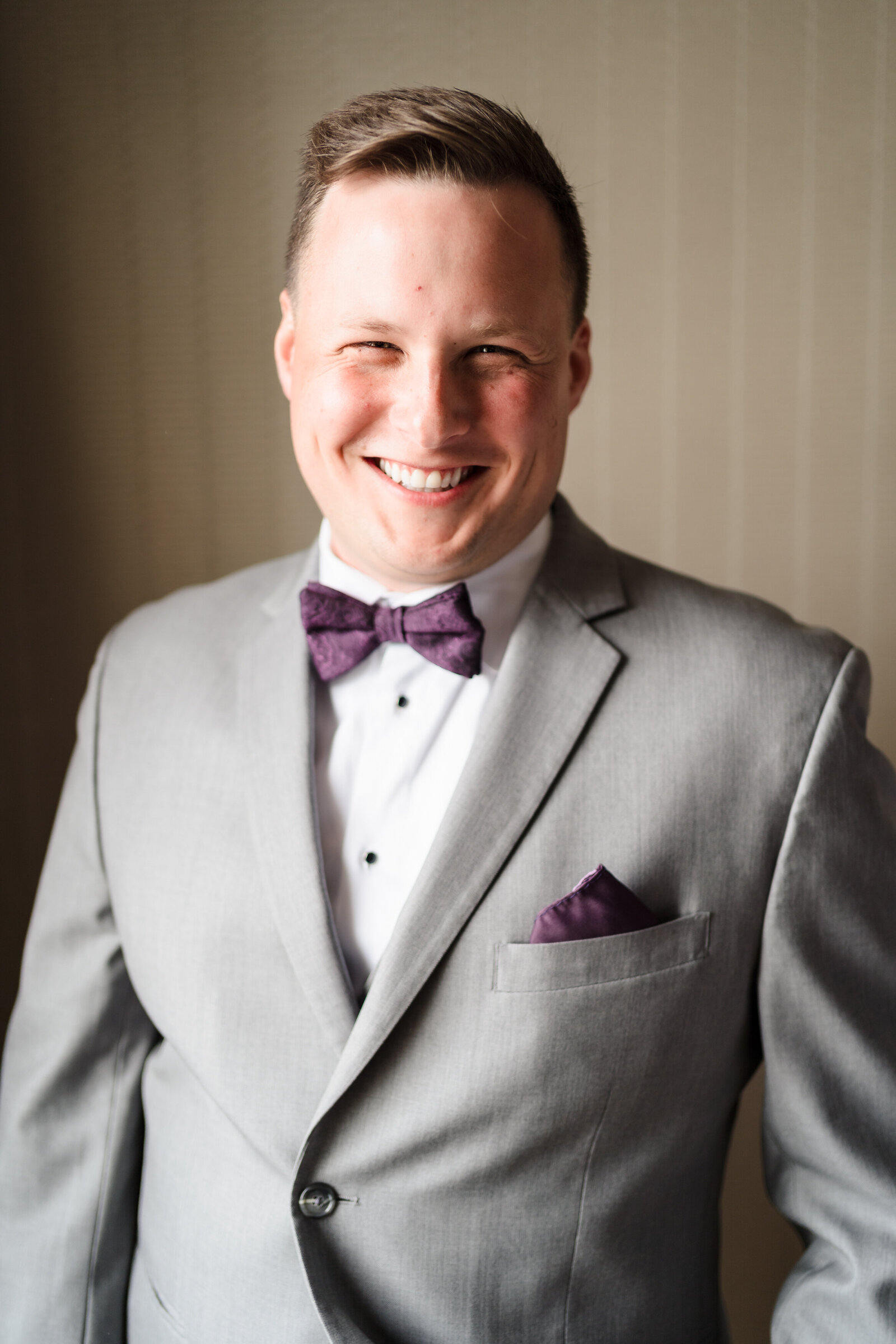 Groom smiles widely after putting on his suit