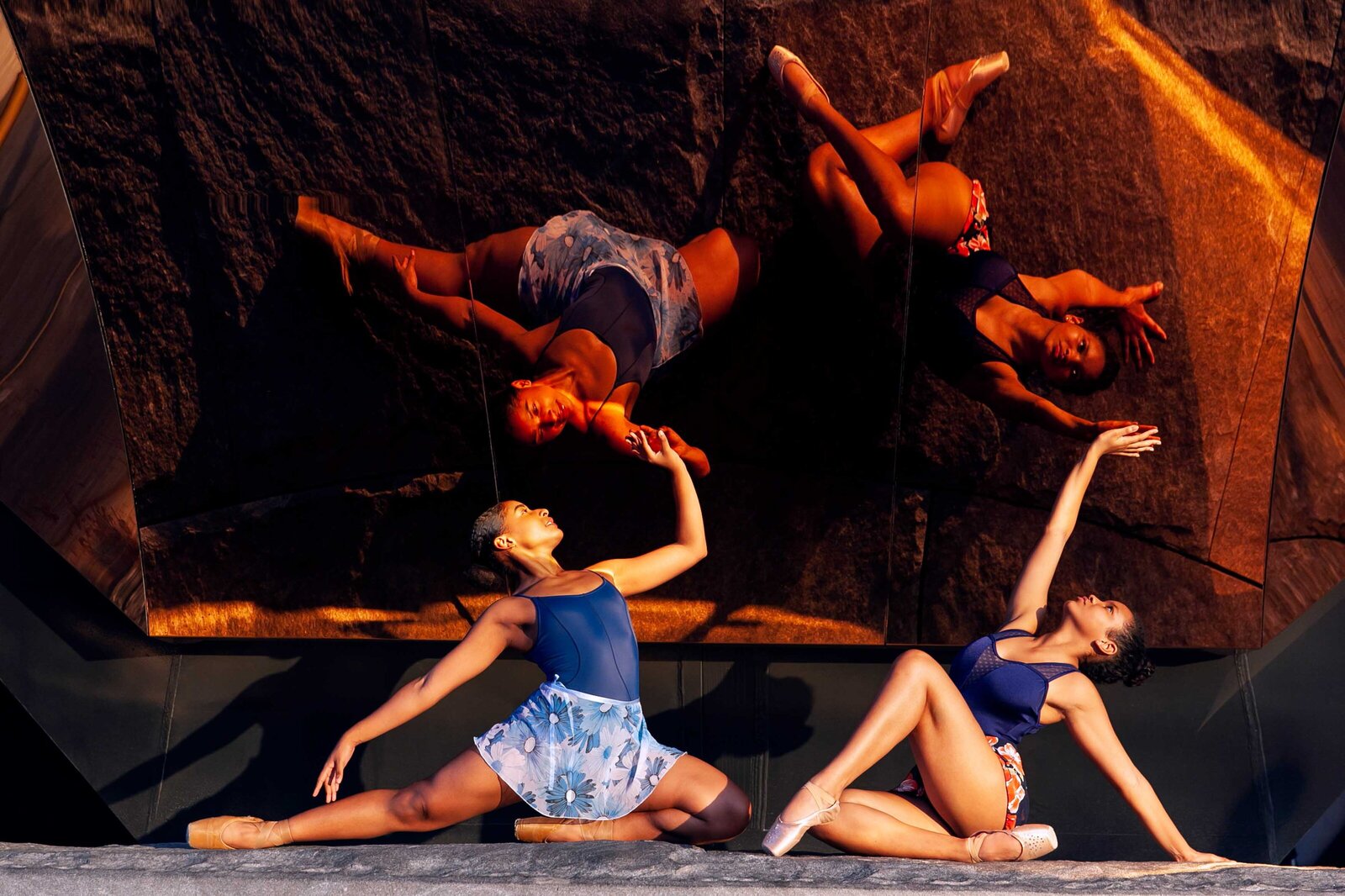 two black ballerinas in seated dance poses looking at their reflection in the Vessel in New York City