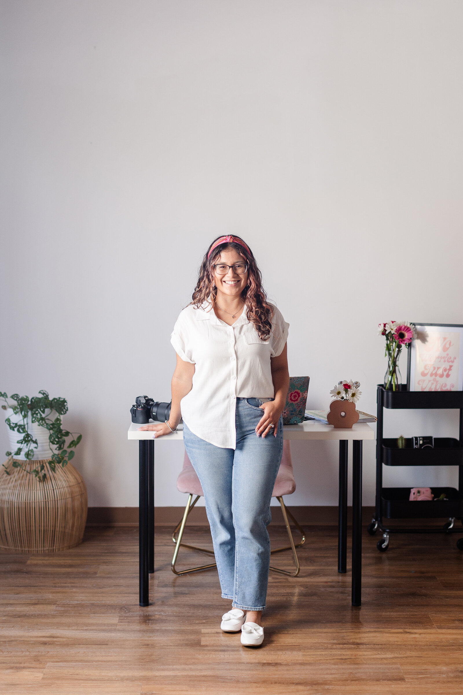 a woman leans on her desk with a smile
