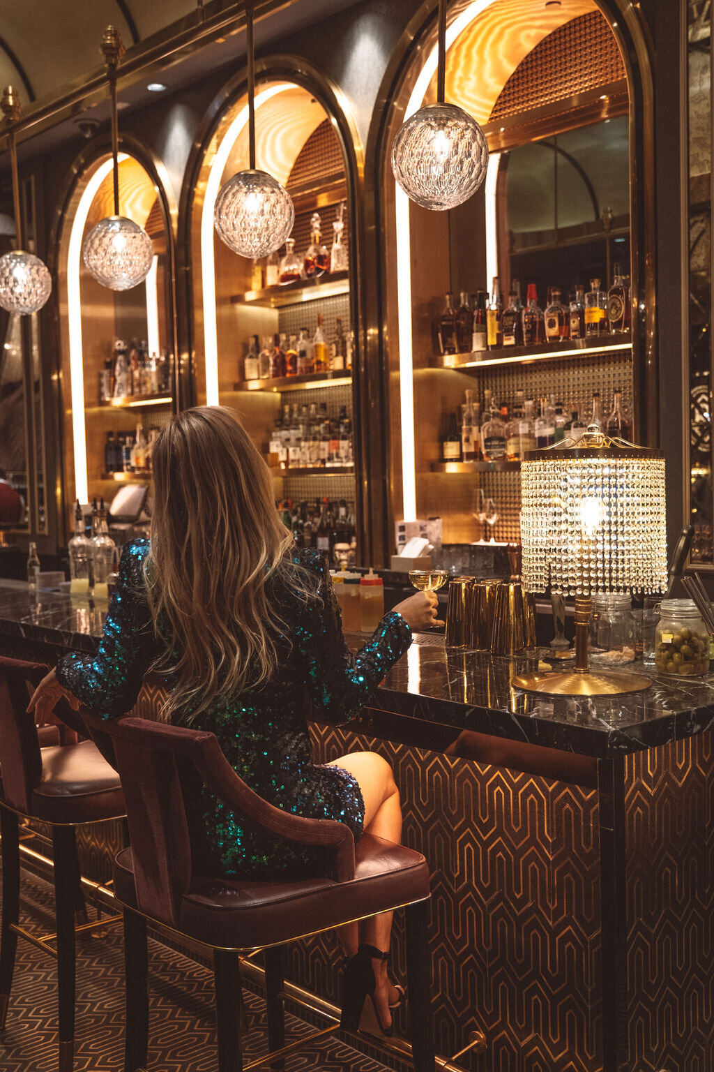 Girl in sparkly dress with curled hair drinking cocktail at 1920s bar in Las Vegas