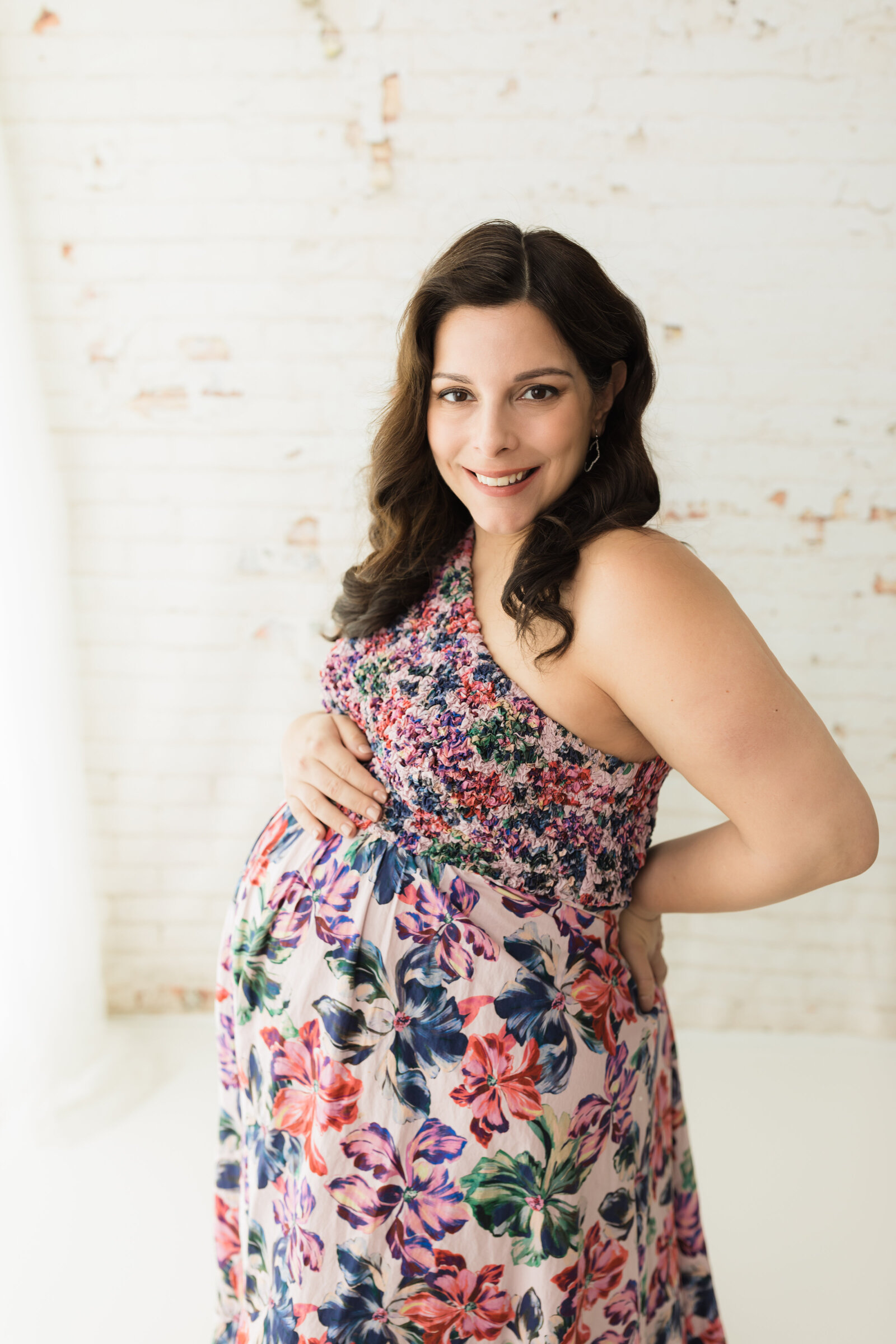 pregnant mother holding baby bump in floral dress for photoshoot 