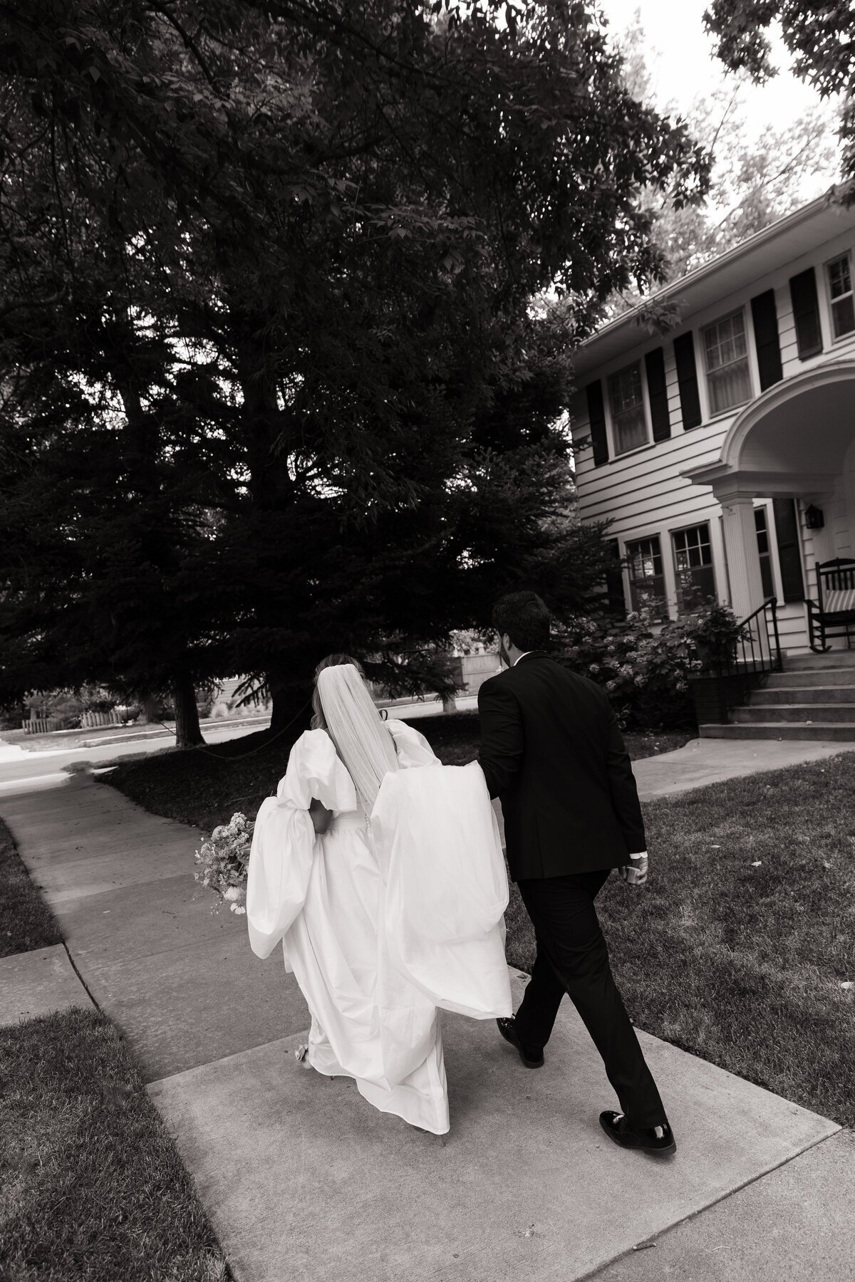 Couple walking down sidewalk in town by destination wedding photographers