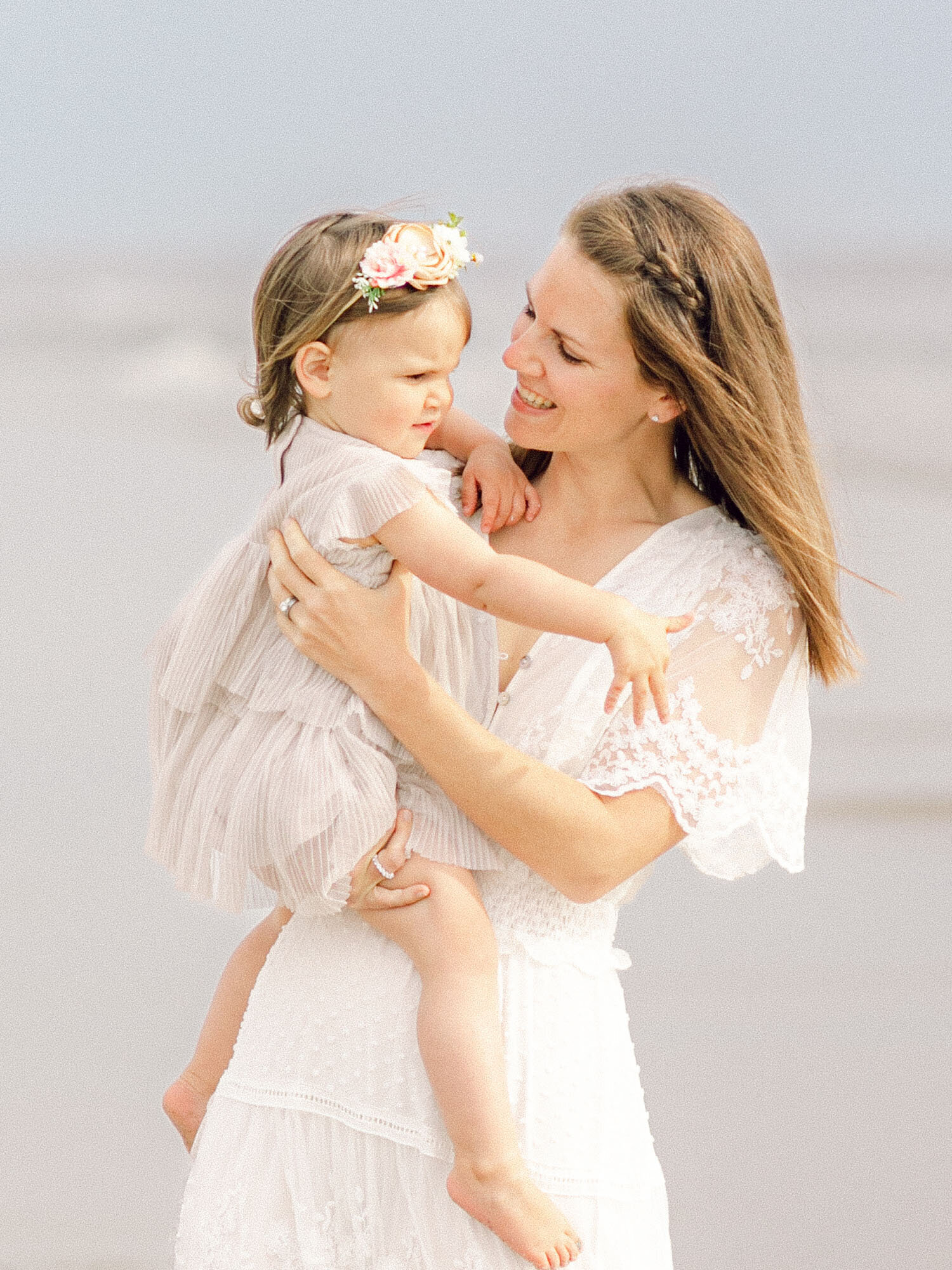 Mother holding and looking at her baby daughter on the beach — close-up by OBX photographers Glenn & Nadya
