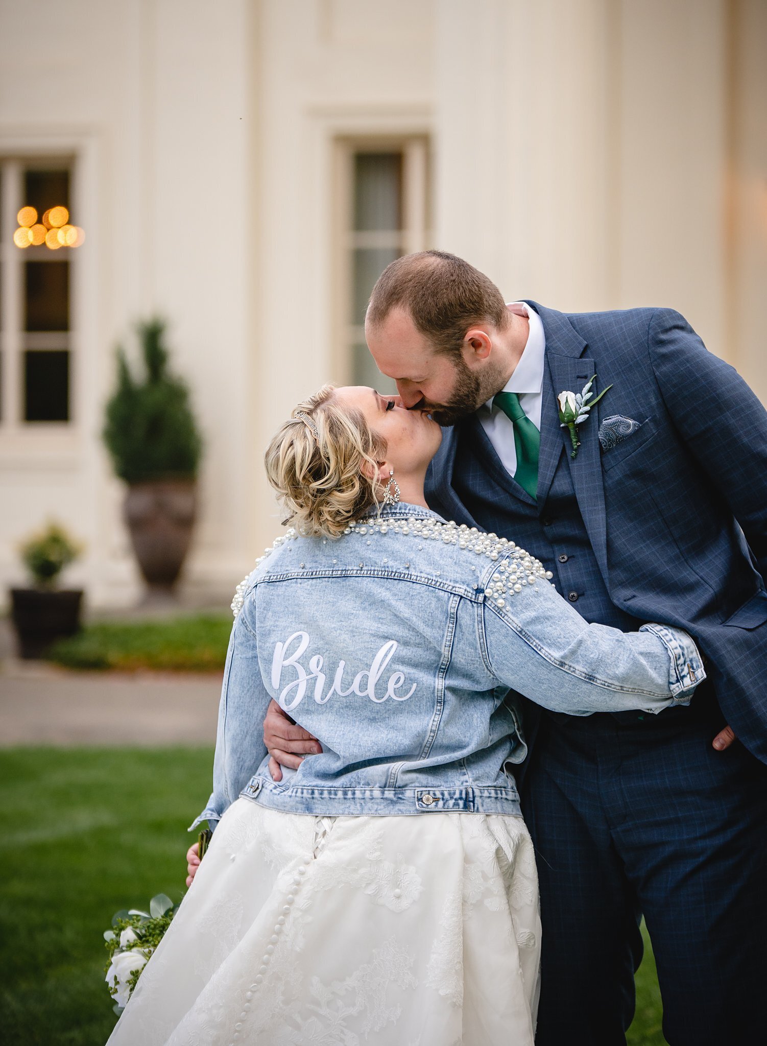 bride in jean jacket kissing groom
