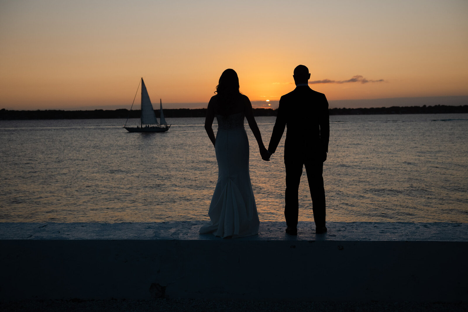 bride and groom hold hands sunset silhouette