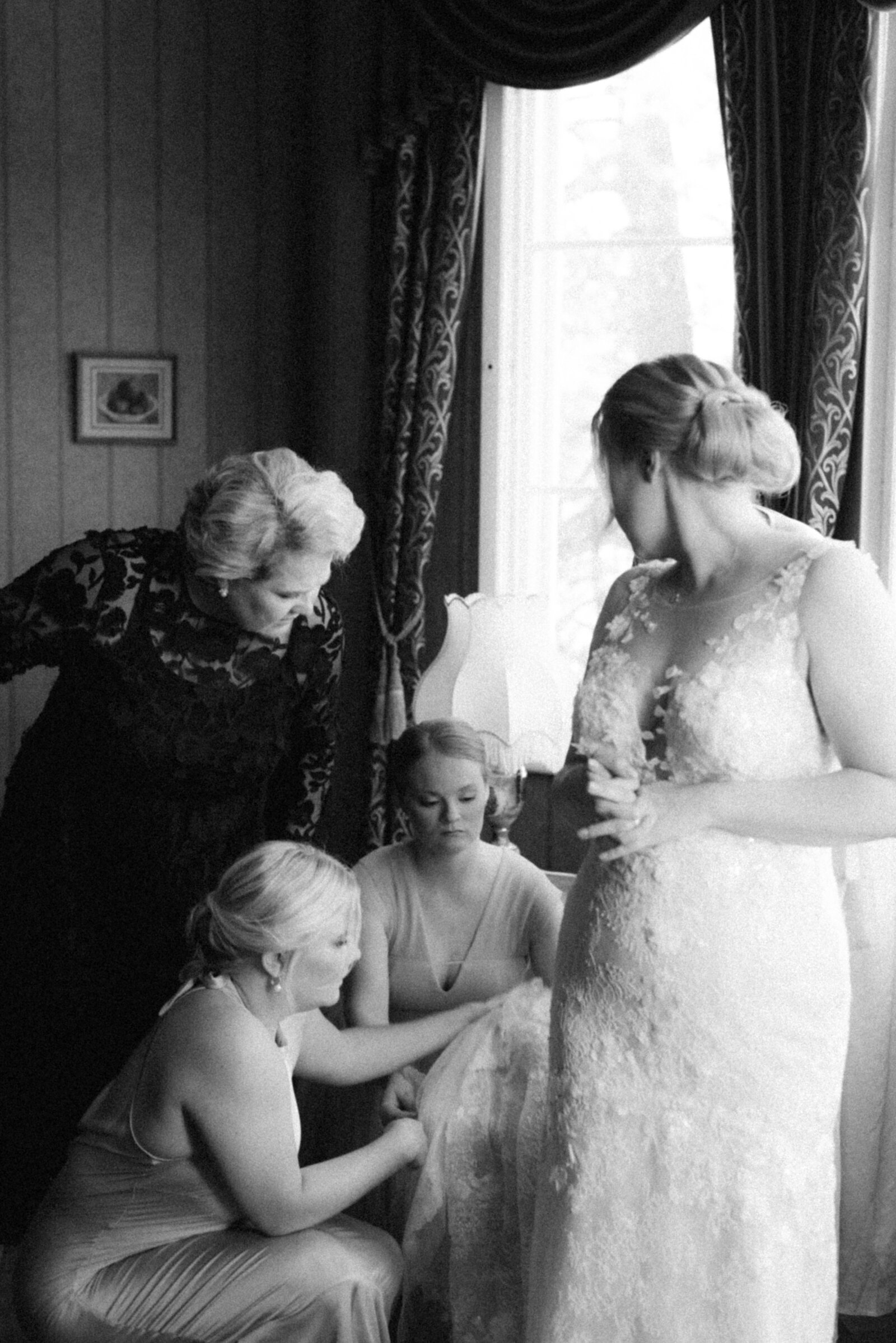 Bridesmaids are solving a problem with the wedding dress in an image photographed by wedding photographer Hannika Gabrielsson.