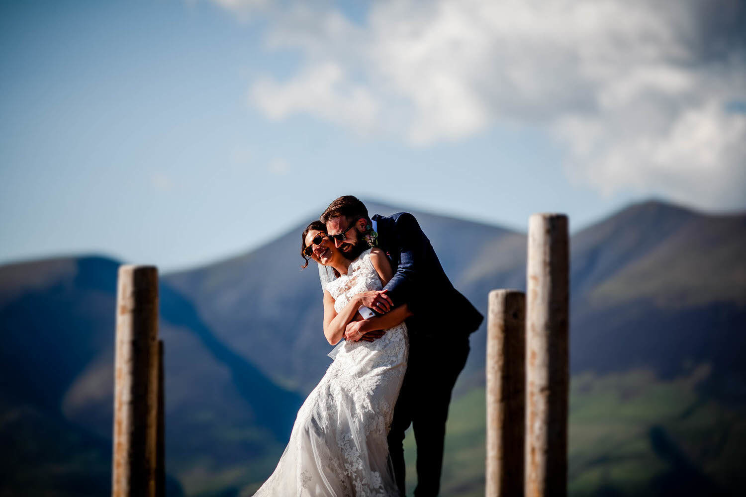wedding couple cuddle on a  jetty in the lake district
