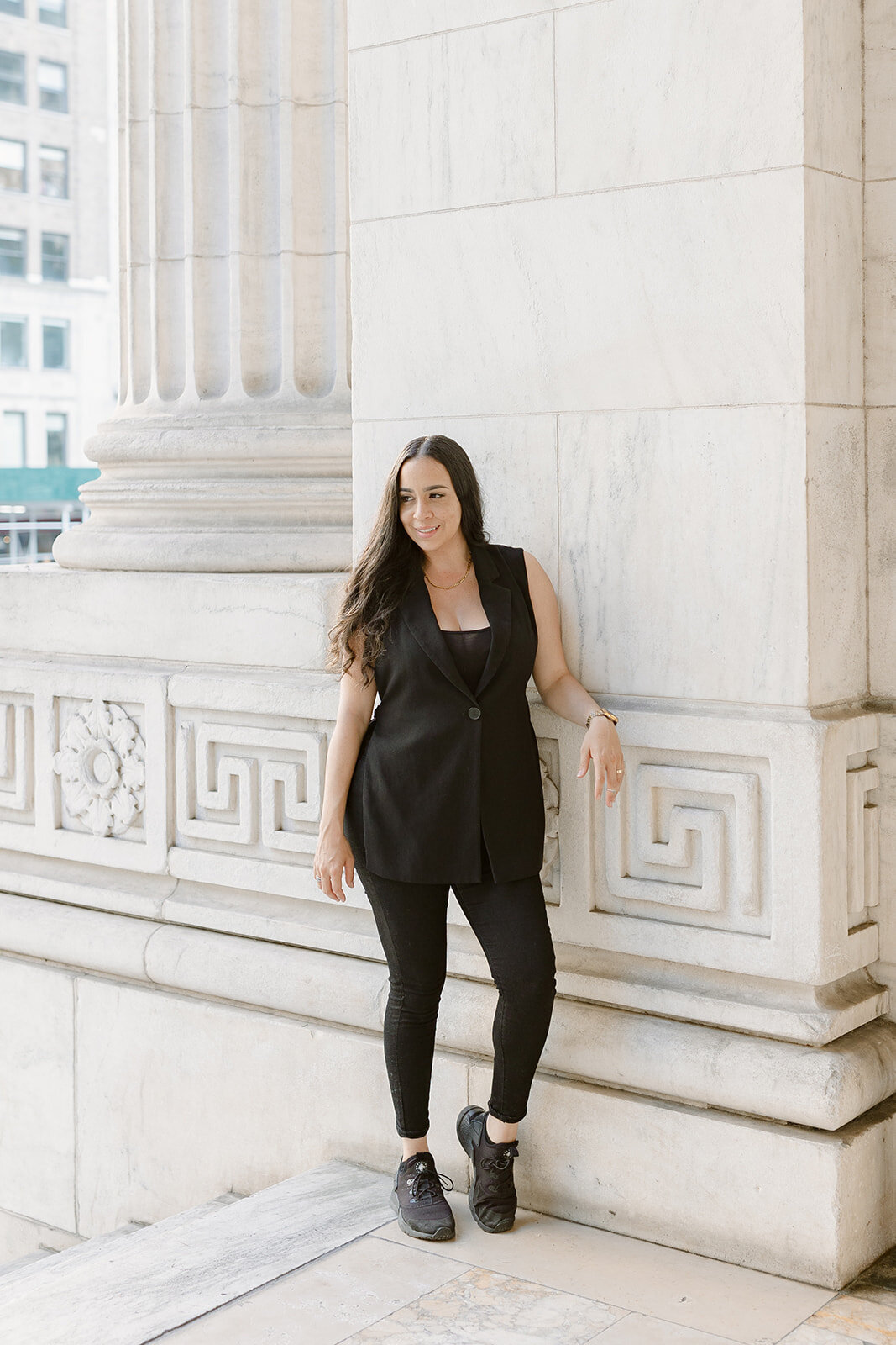 Florida wedding photographer, Melanie Anne, smiles wearing white blouse against white wall