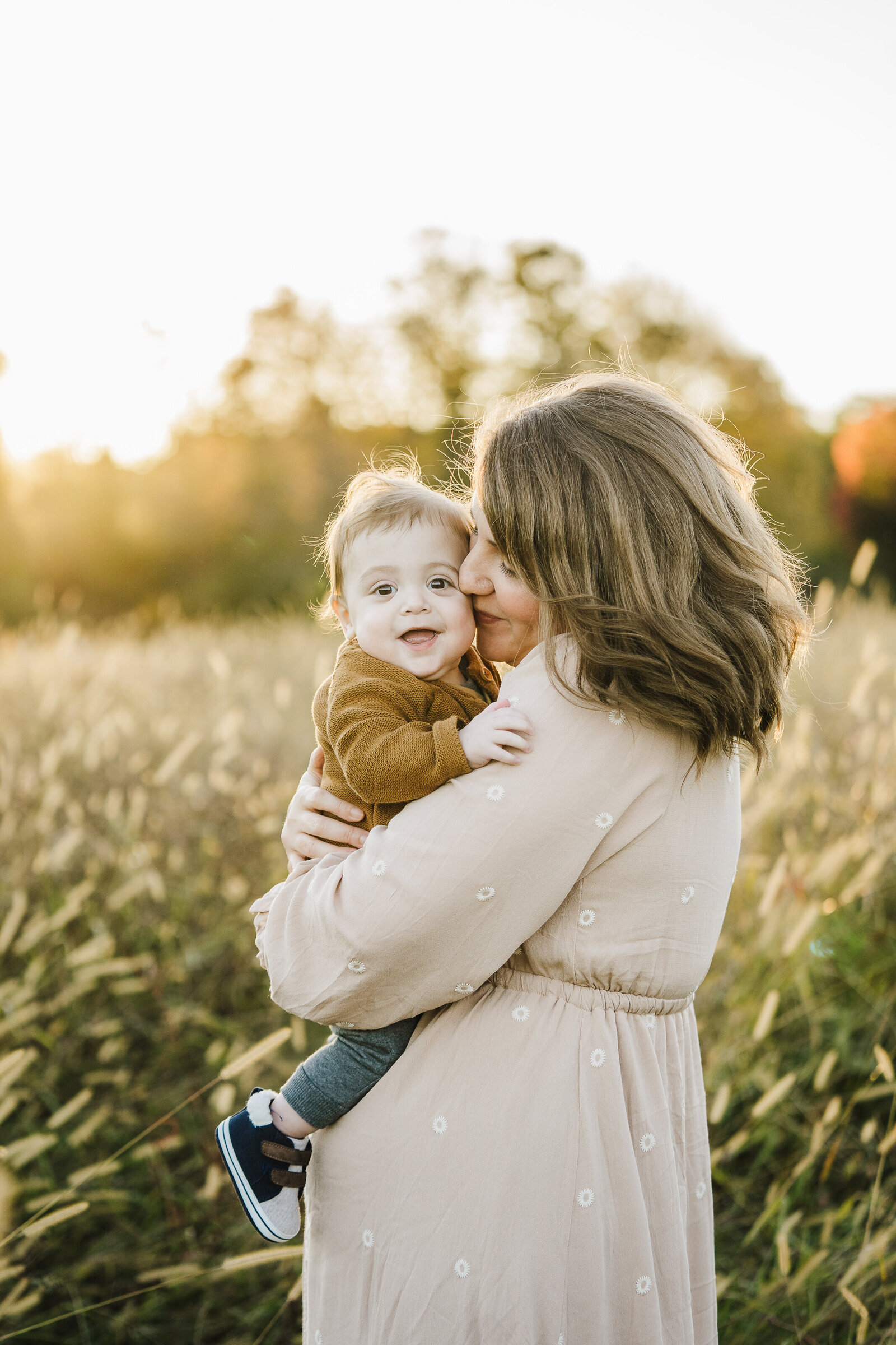 mom kisses baby boy at sunset