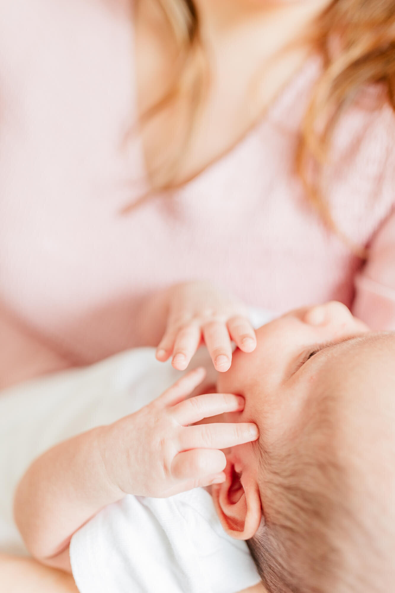 Close up detail image of newborn's hands next to her face