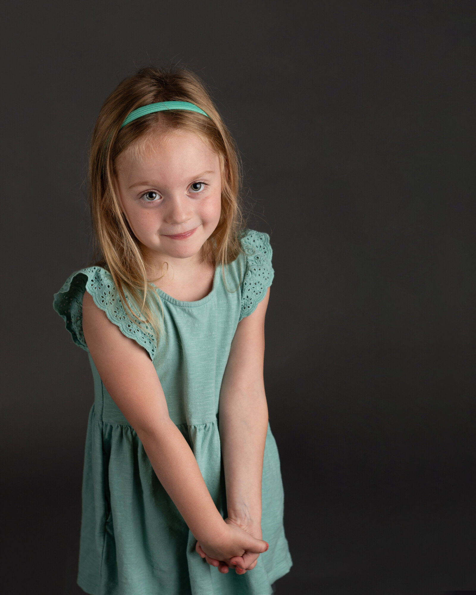 School photo of young girl wearing a dress and headband .