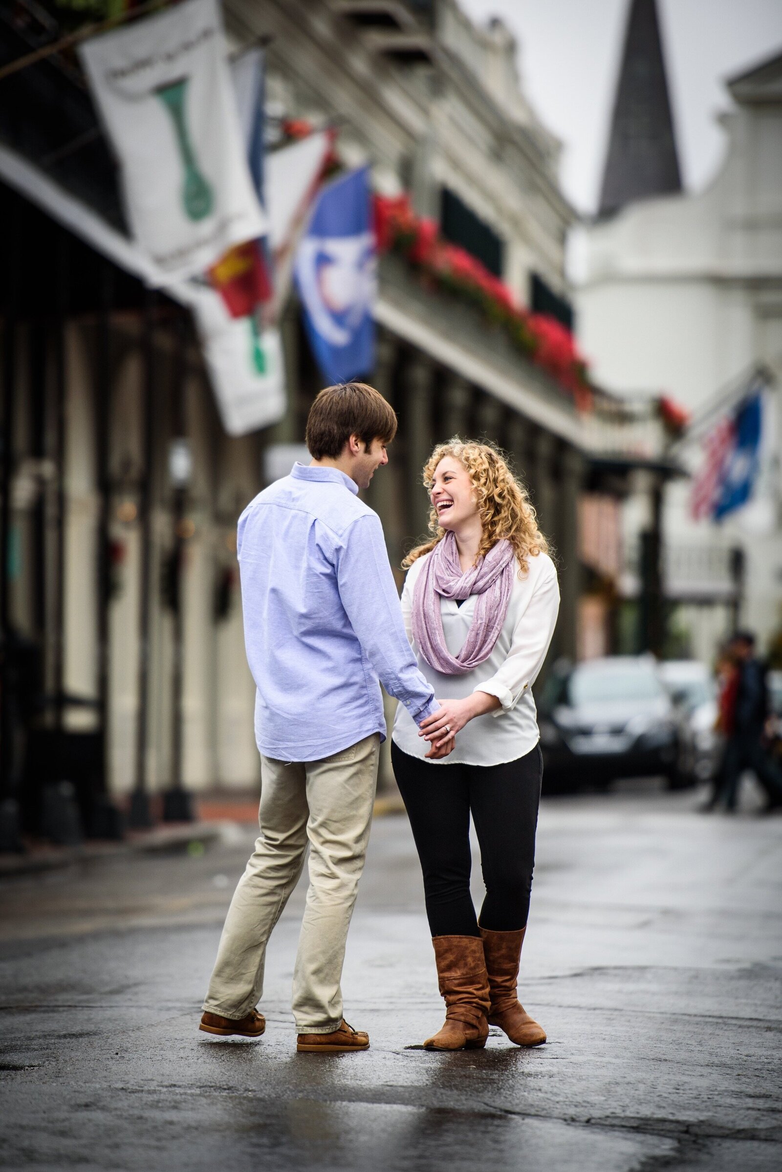 Engagement portrait in the French Quarter with flags in the background and wet street