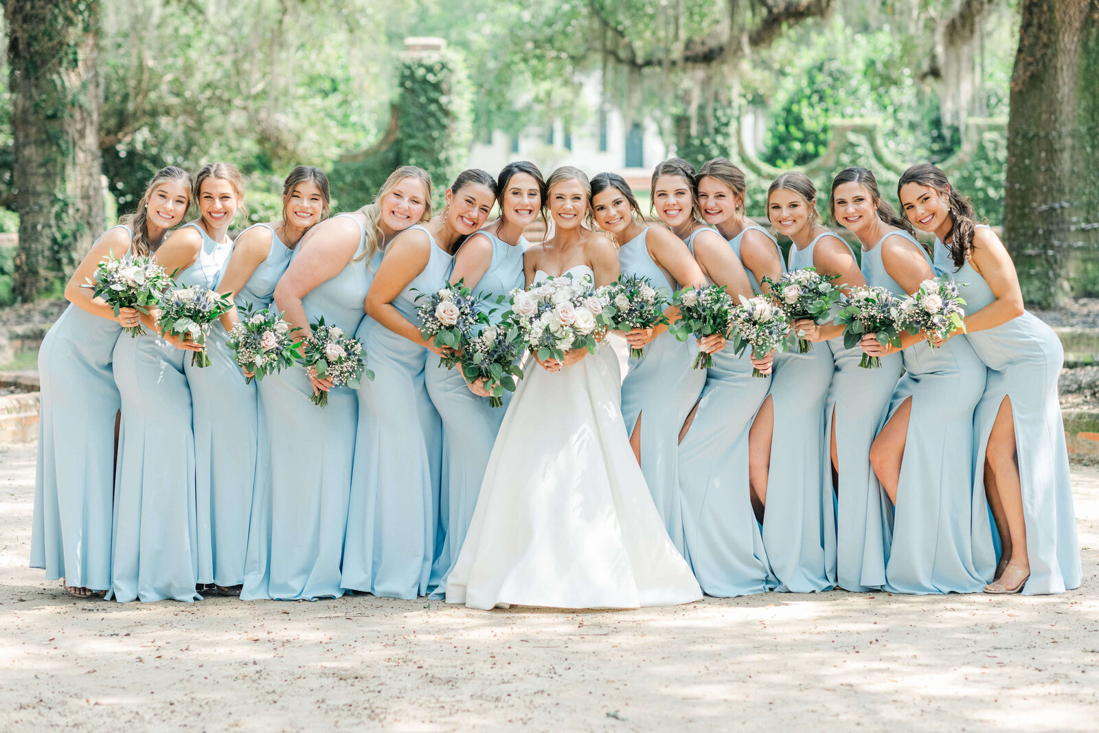 Bride in center surrounded by bridesmaids in powder blue dresses all holding wedding bouquets