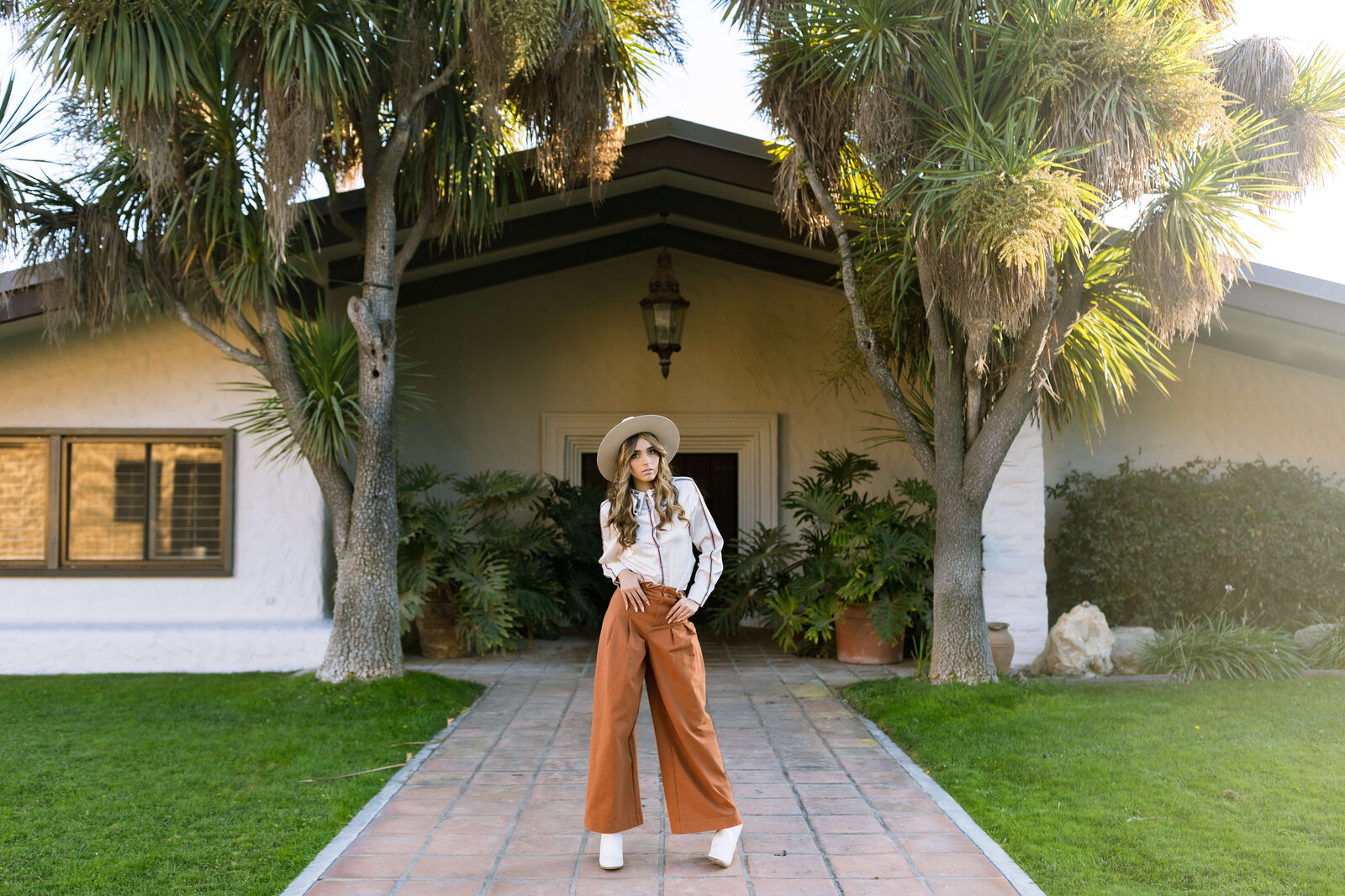 Girl wearing wide leg pants and cute hat posing in front of home