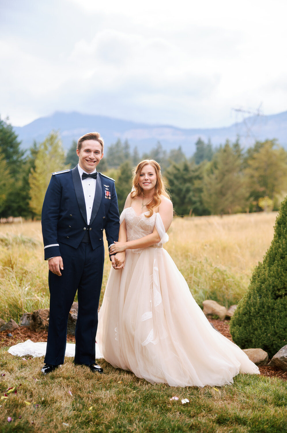 Bride and groom hold hands with mountains in the background