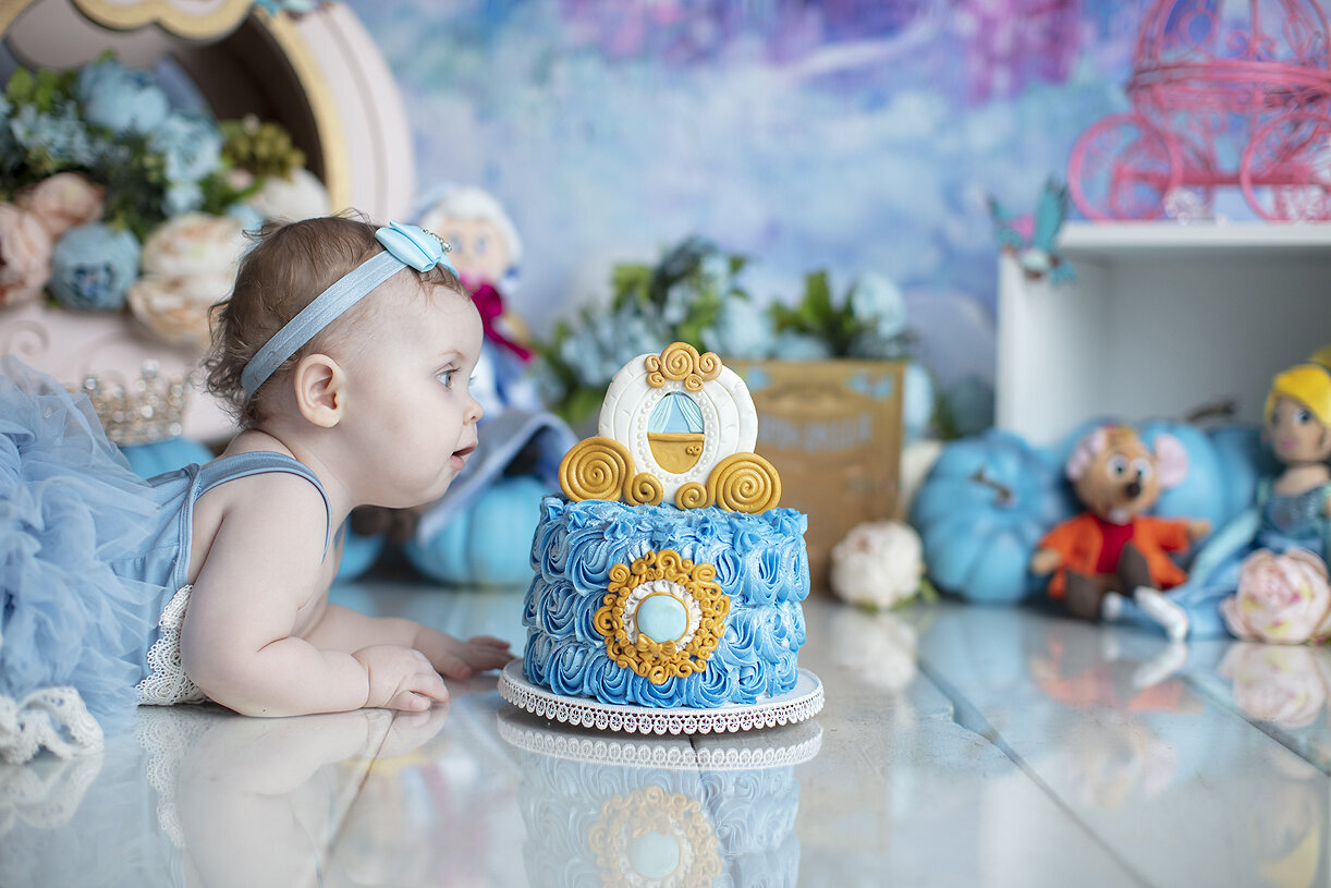 Baby looking at first birthday cake.