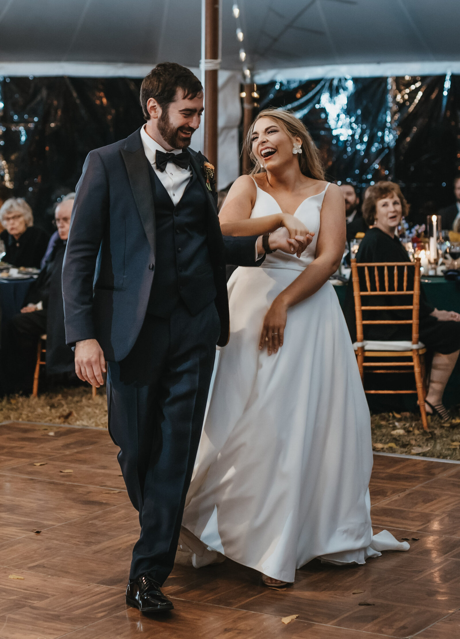 A bride and groom laugh on the dance floor