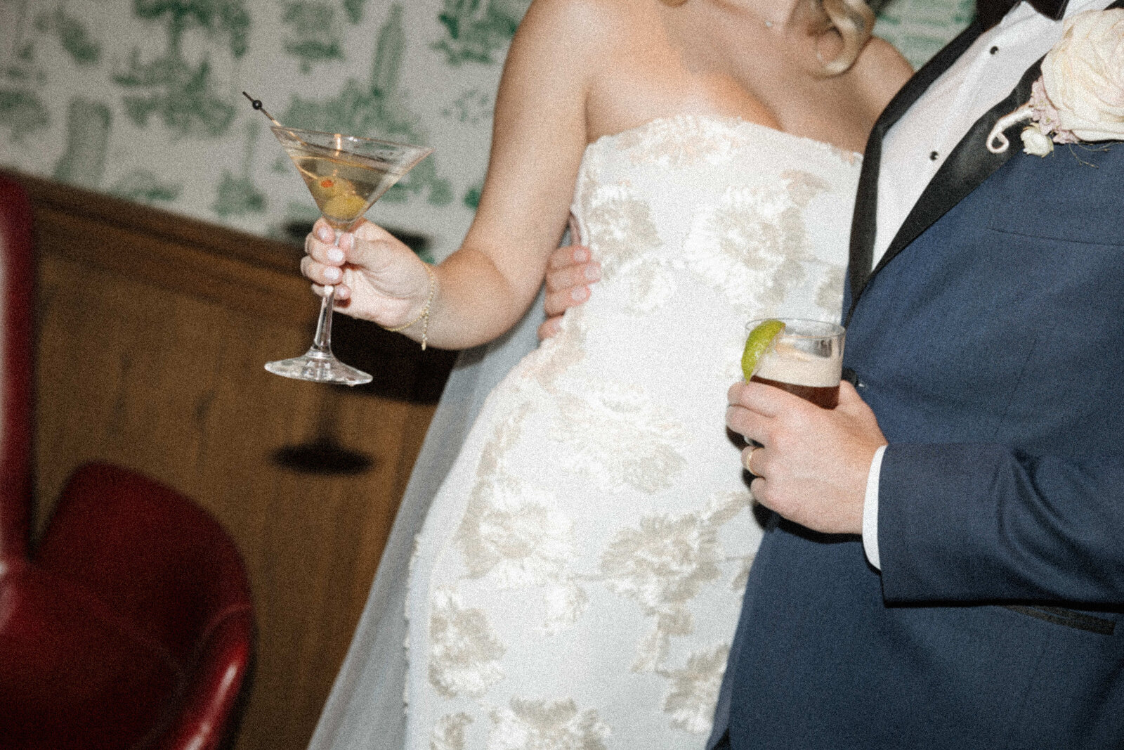 A bride holding a martini and a groom holding his cocktail. Showing off the drinks. 