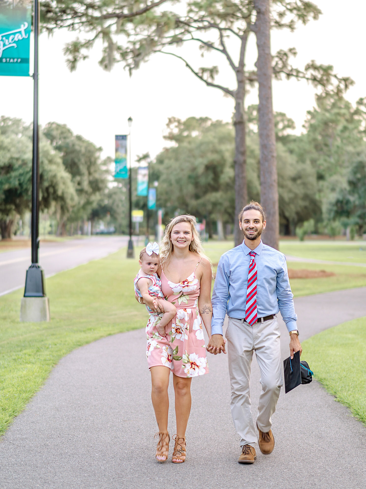A graduate in a tie walking with his family along a UNCW campus path in Wilmington, North Carolina. This image captures the joy and celebration of graduation, ideal for capturing memorable family moments.