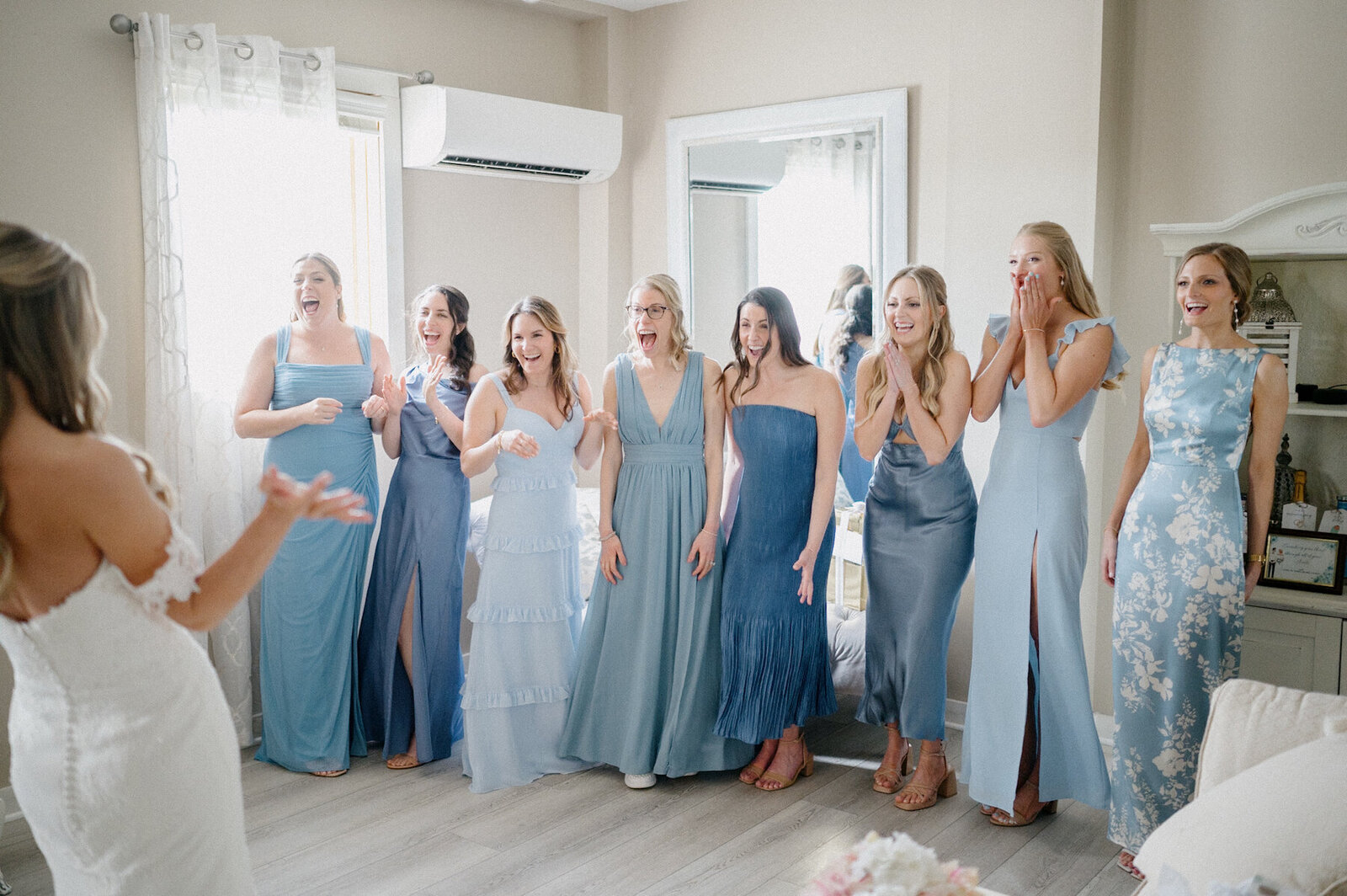 Bridesmaids in blue dresses reacting to bride reveal
