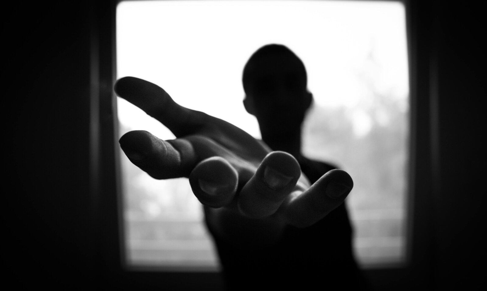 Image of a silhouette of a bald person extending their hand