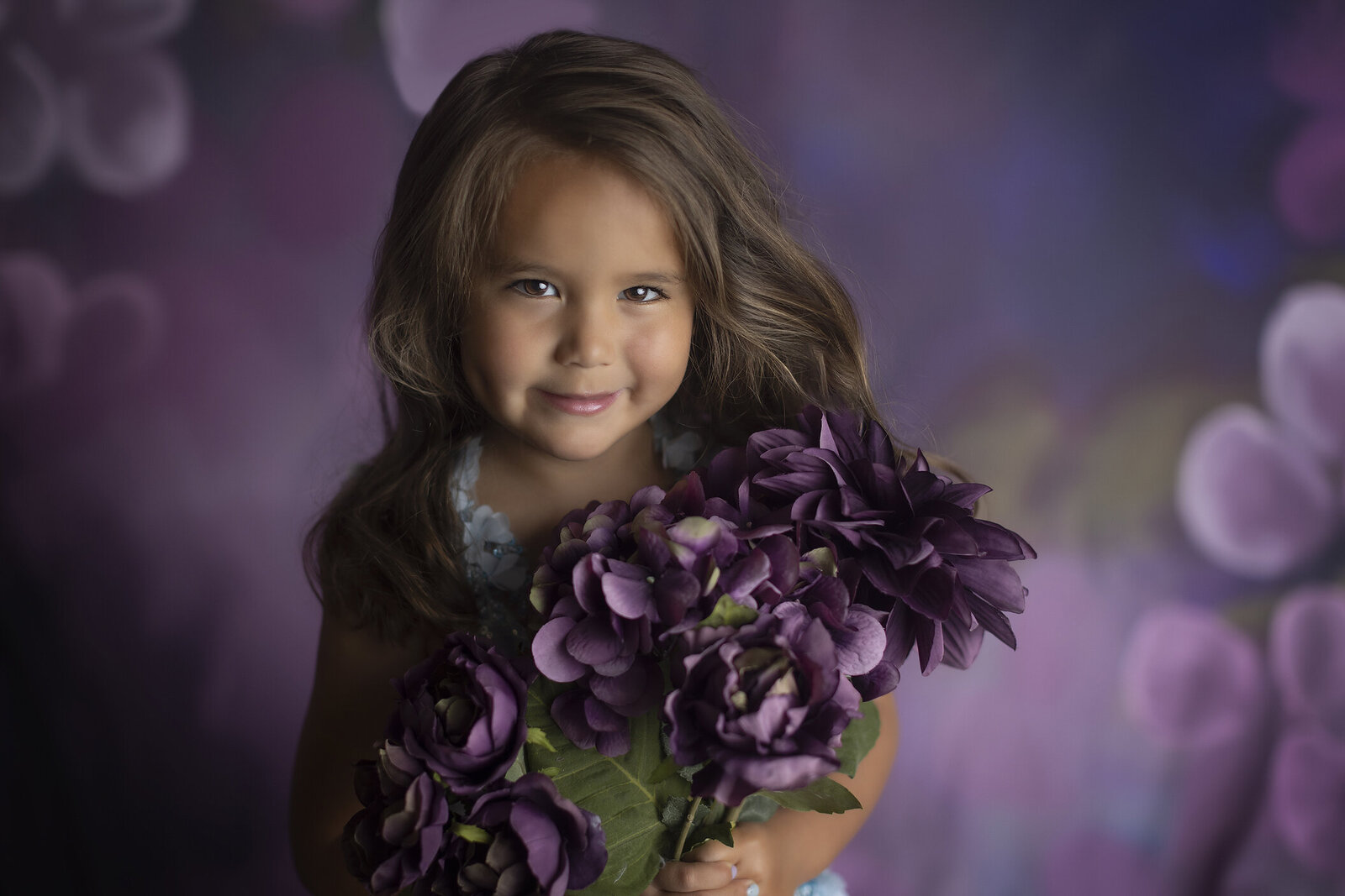 Girl holding flowers in coture gown at Dallas children’s photographer.
