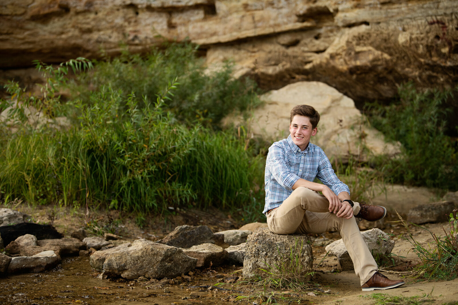 high school senior photo of boy  with rocks and cliffs in Stillwater