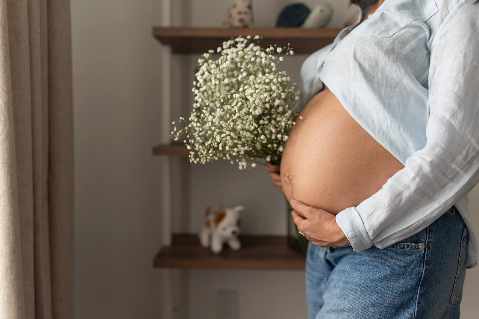 Expecting mom holds baby's breath flowers near her belly