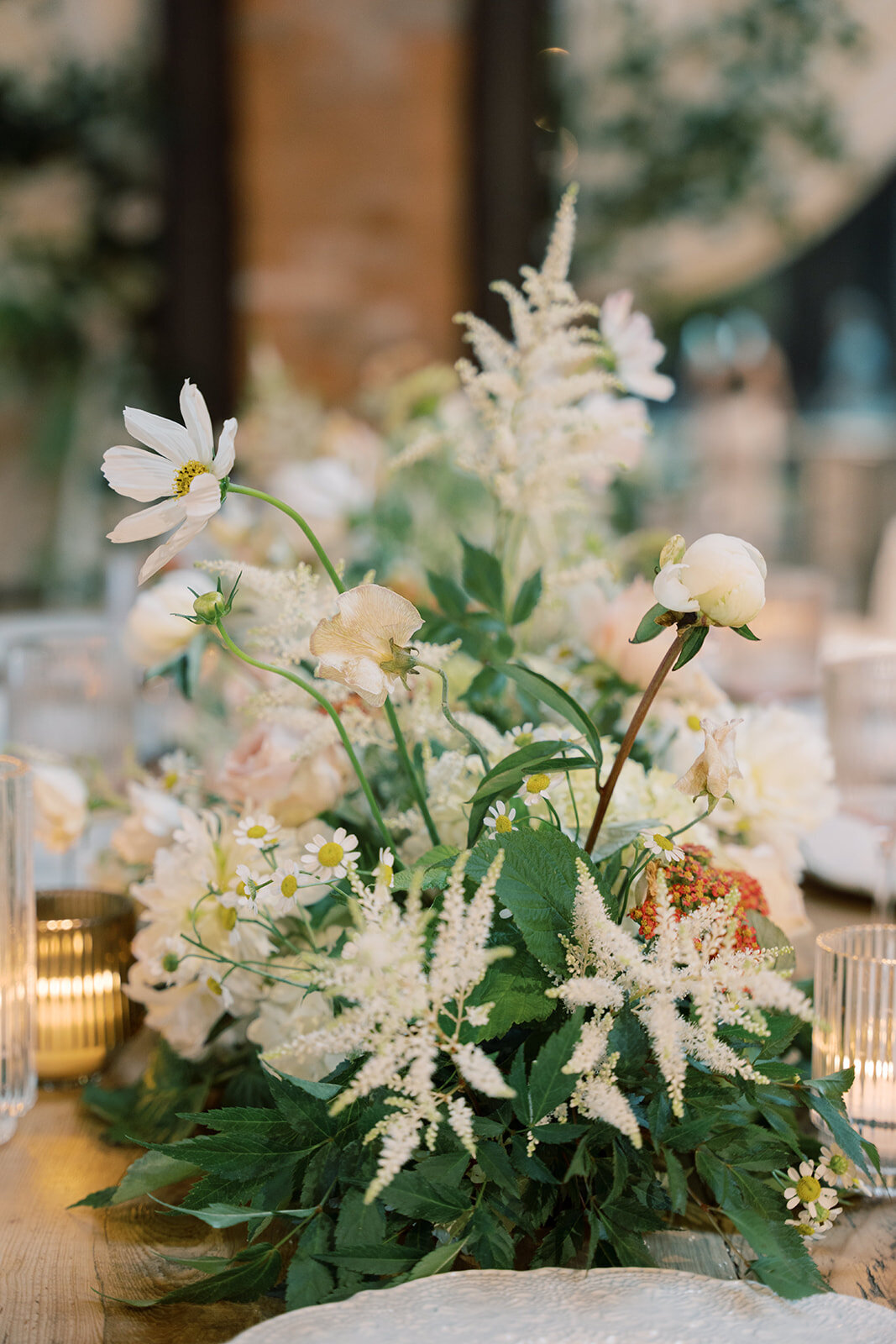 Florals on the table including white astilbe, white peony bud, white cosmos, daisies, cream sweet pea, and wild raspberry leaf.