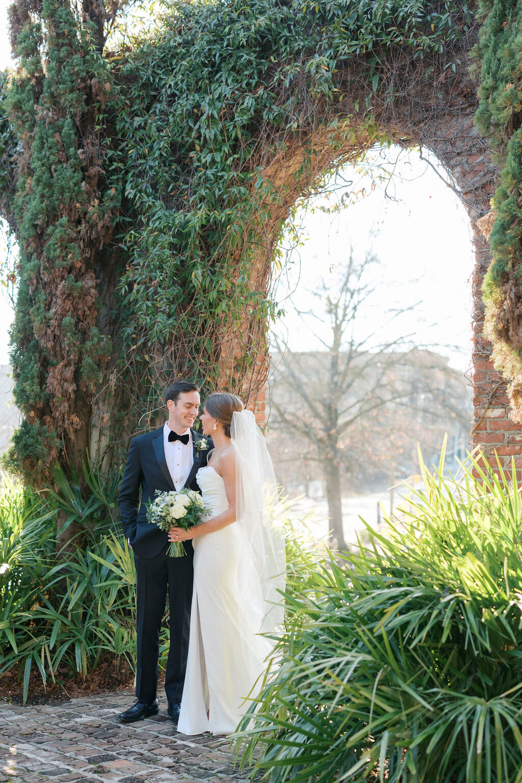 Bride and groom kiss outside of ivy covered arch at Summerour Studio