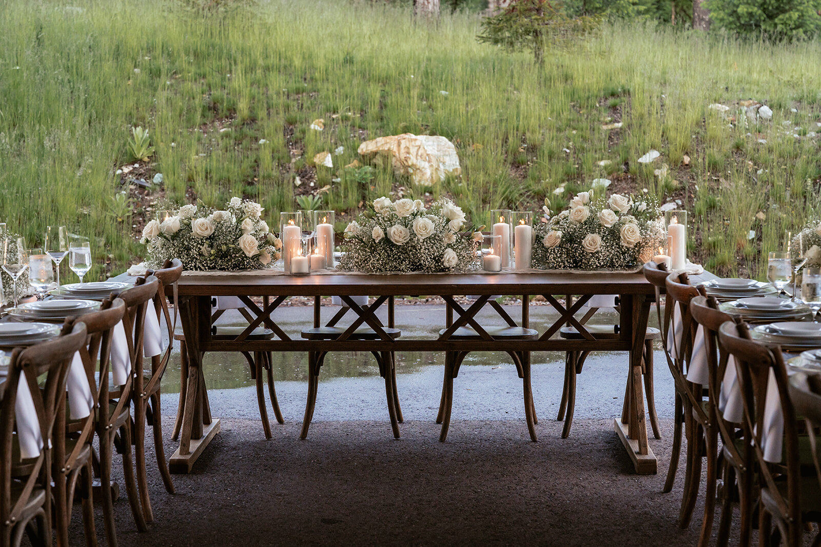 Elegant sweetheart-style elopement table with candles, white roses, and baby’s breath, designed for an intimate celebration surrounded by nature.