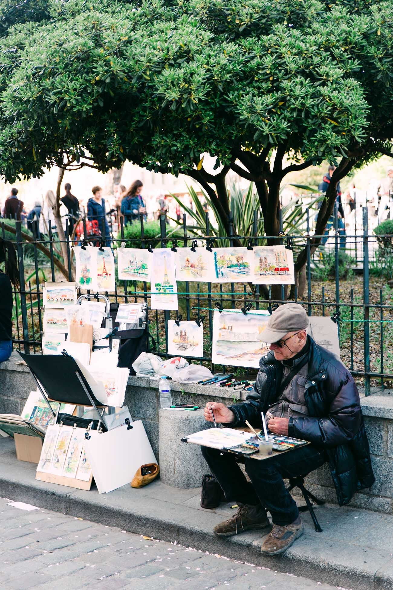 Man painting on the sidewalk street artist near Shakespeare and Co in Paris, France. Chelsea Loren is based in San Diego, California
