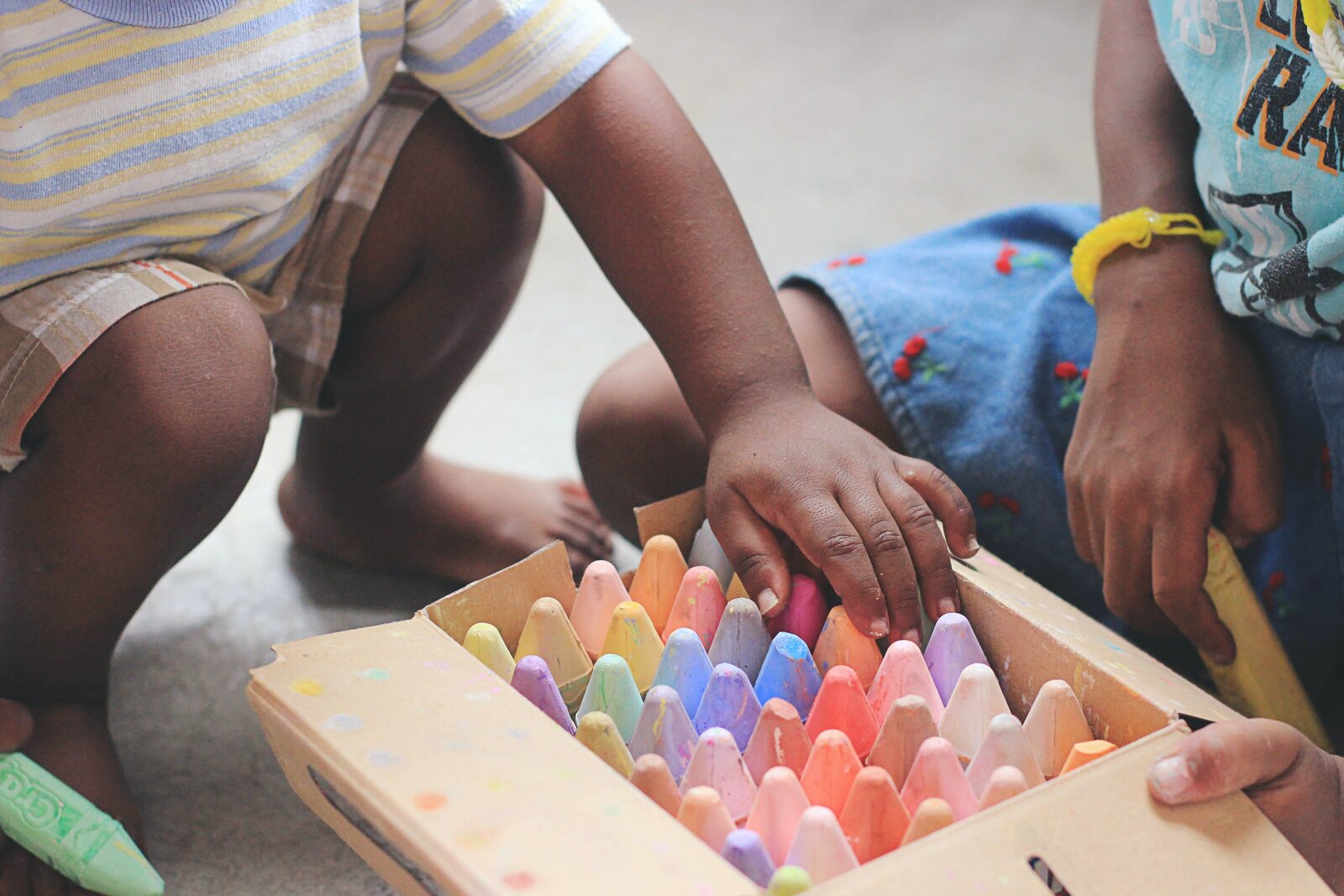 kids reaching into box of chalk