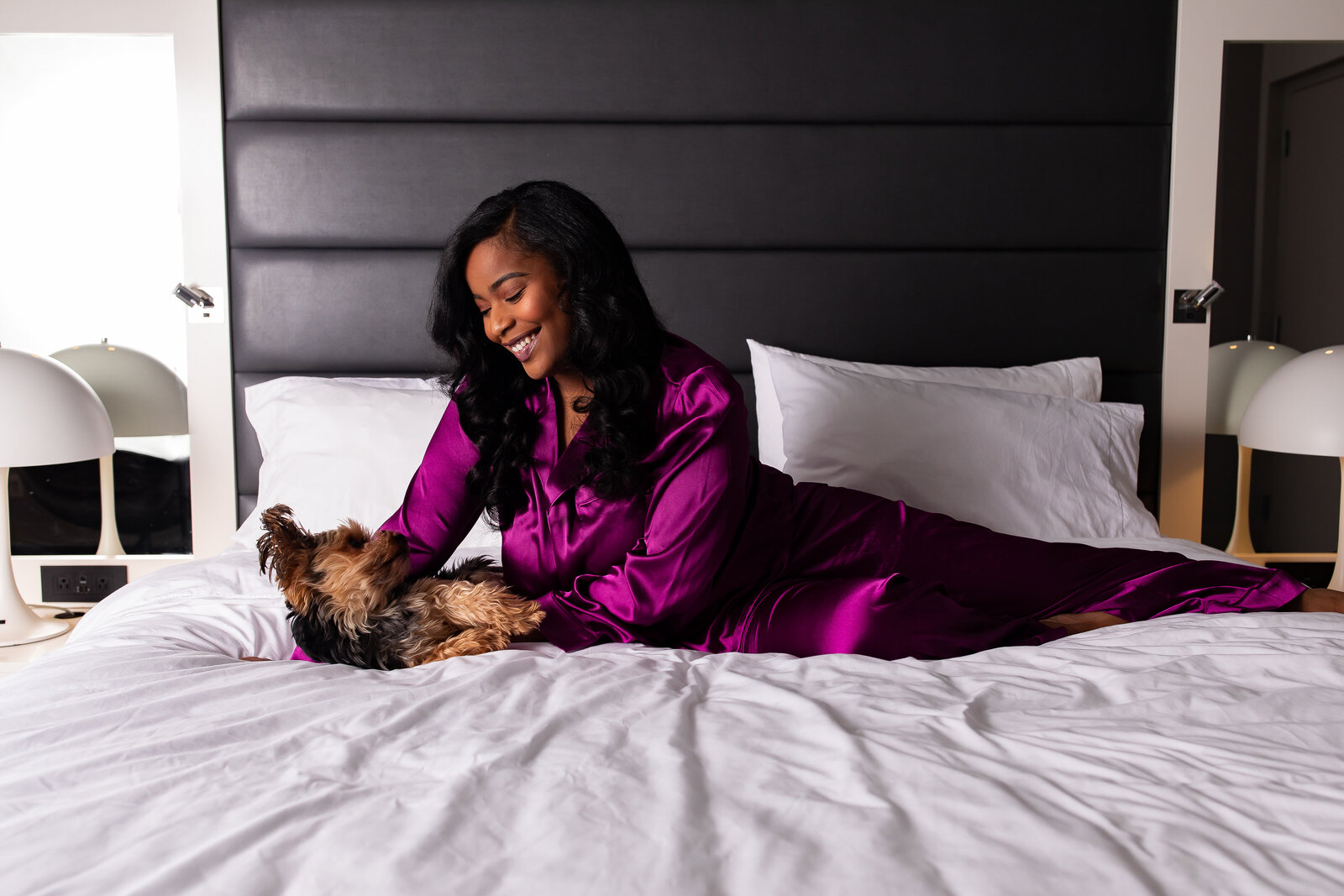 Woman playing with puppy  on a bed in the  Renaissance  Albany hotel