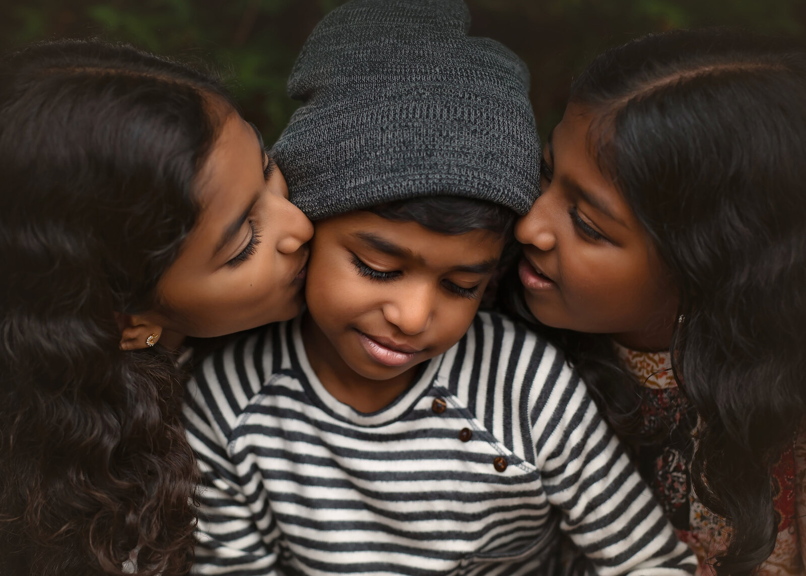 sisters kissing brother on cheek